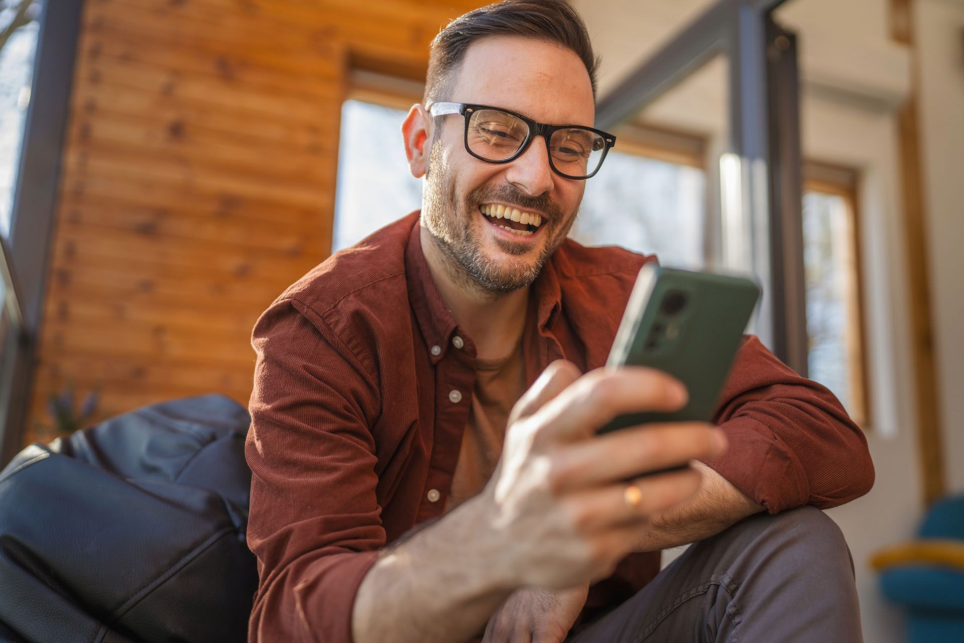 Man laughing, looking at his phone.