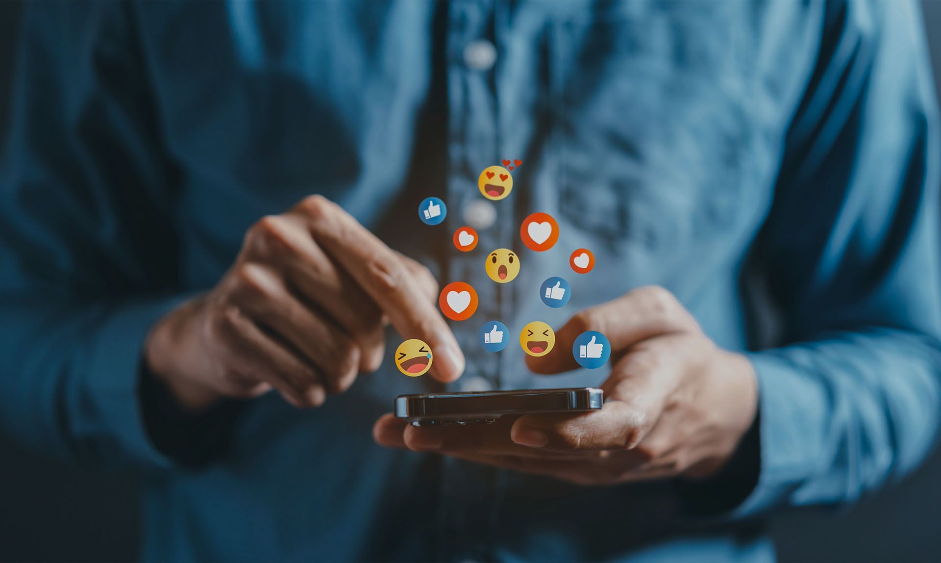 A man is using a smart phone with social media icons coming out of it.