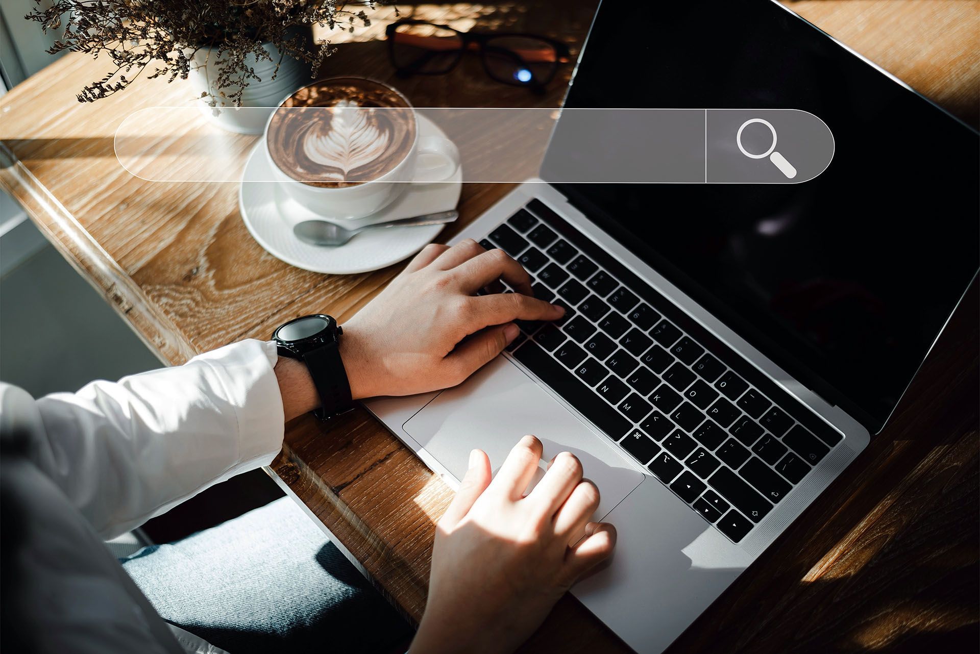 Person using laptop at a cafe, searching online with a coffee nearby.
