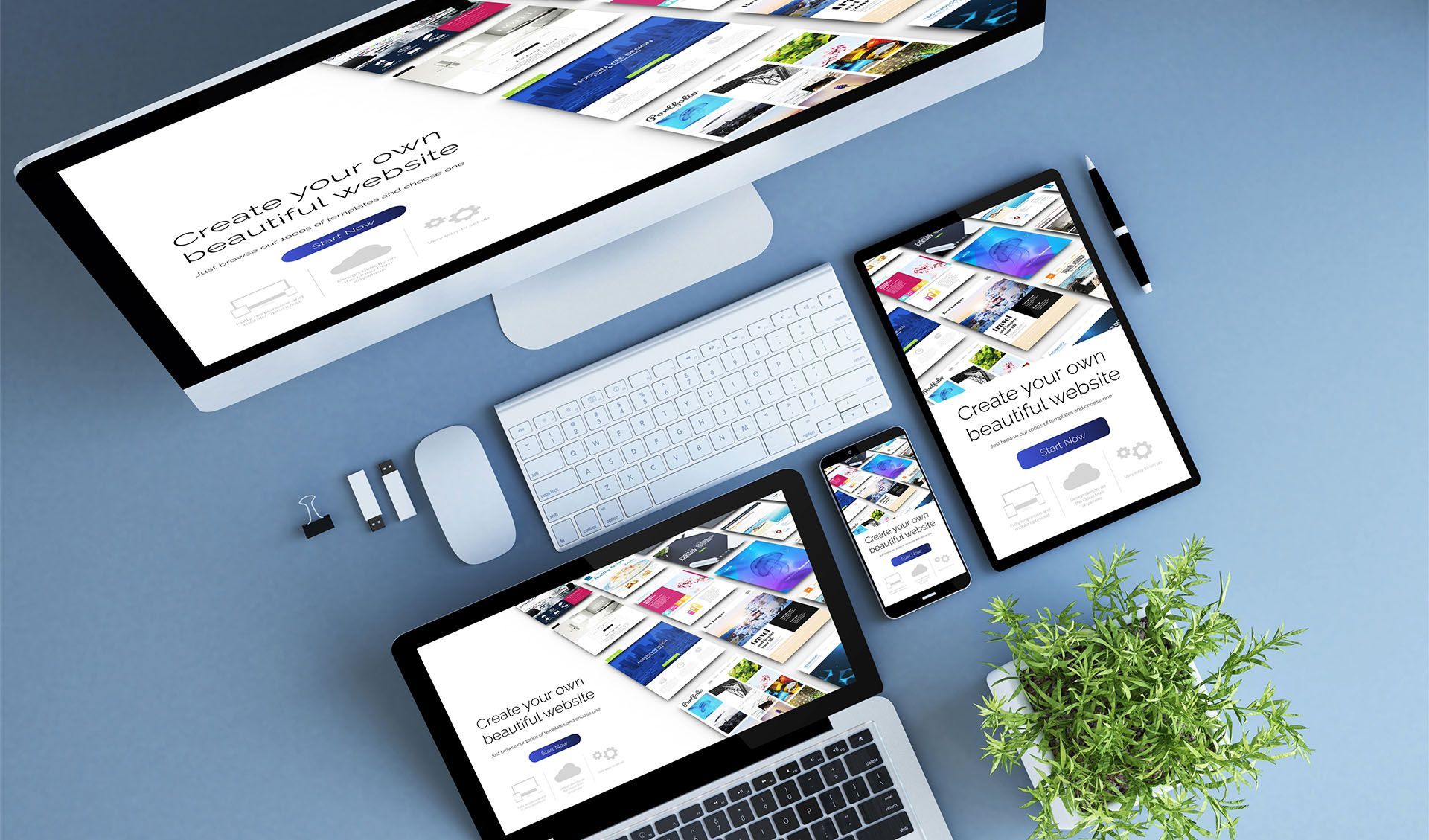 Desktop, laptop, tablet, and phone displaying the same website layout on a blue surface, with a white keyboard and mouse, a plant.