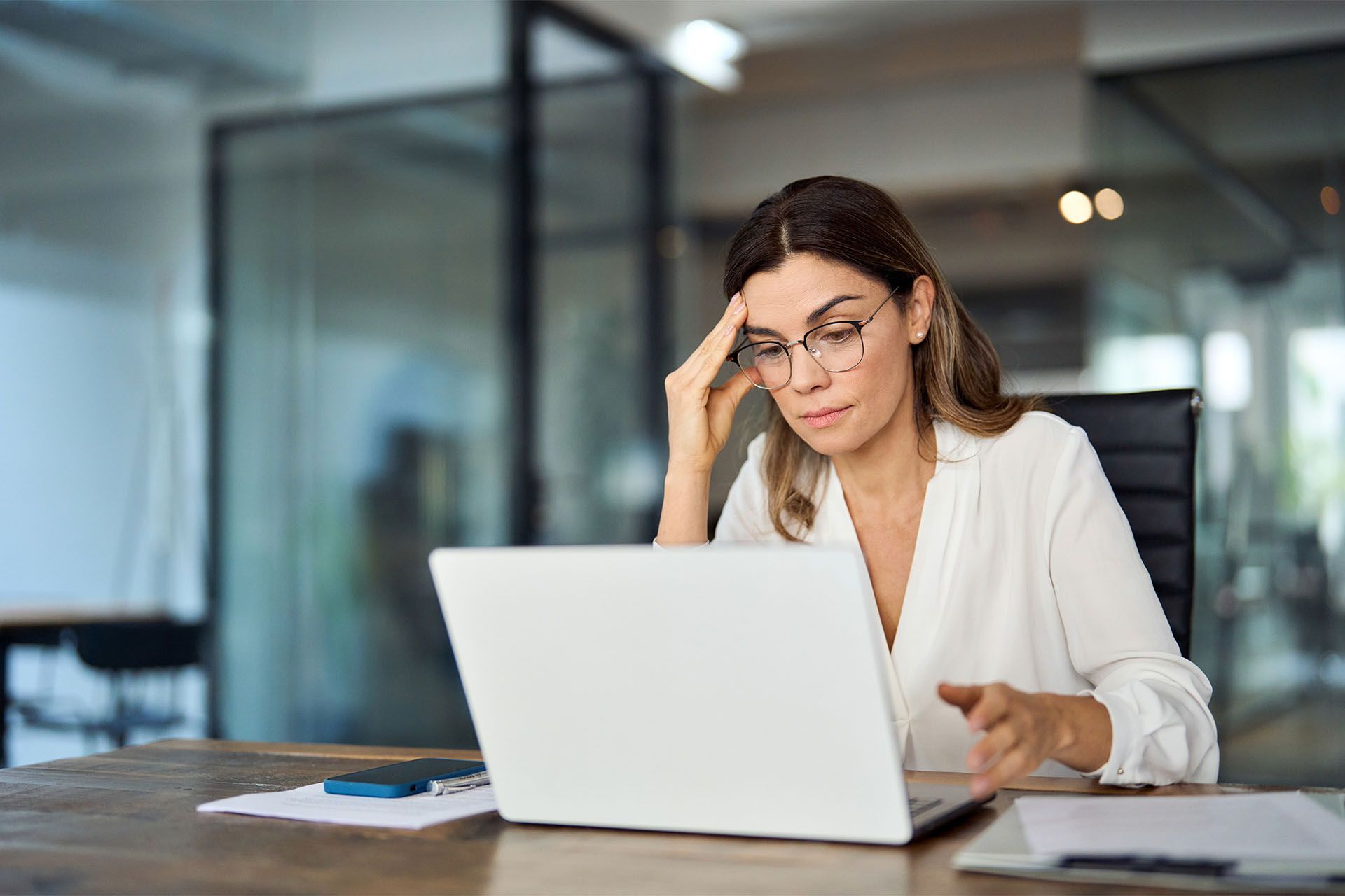 A woman is sitting at a desk using a laptop computer.