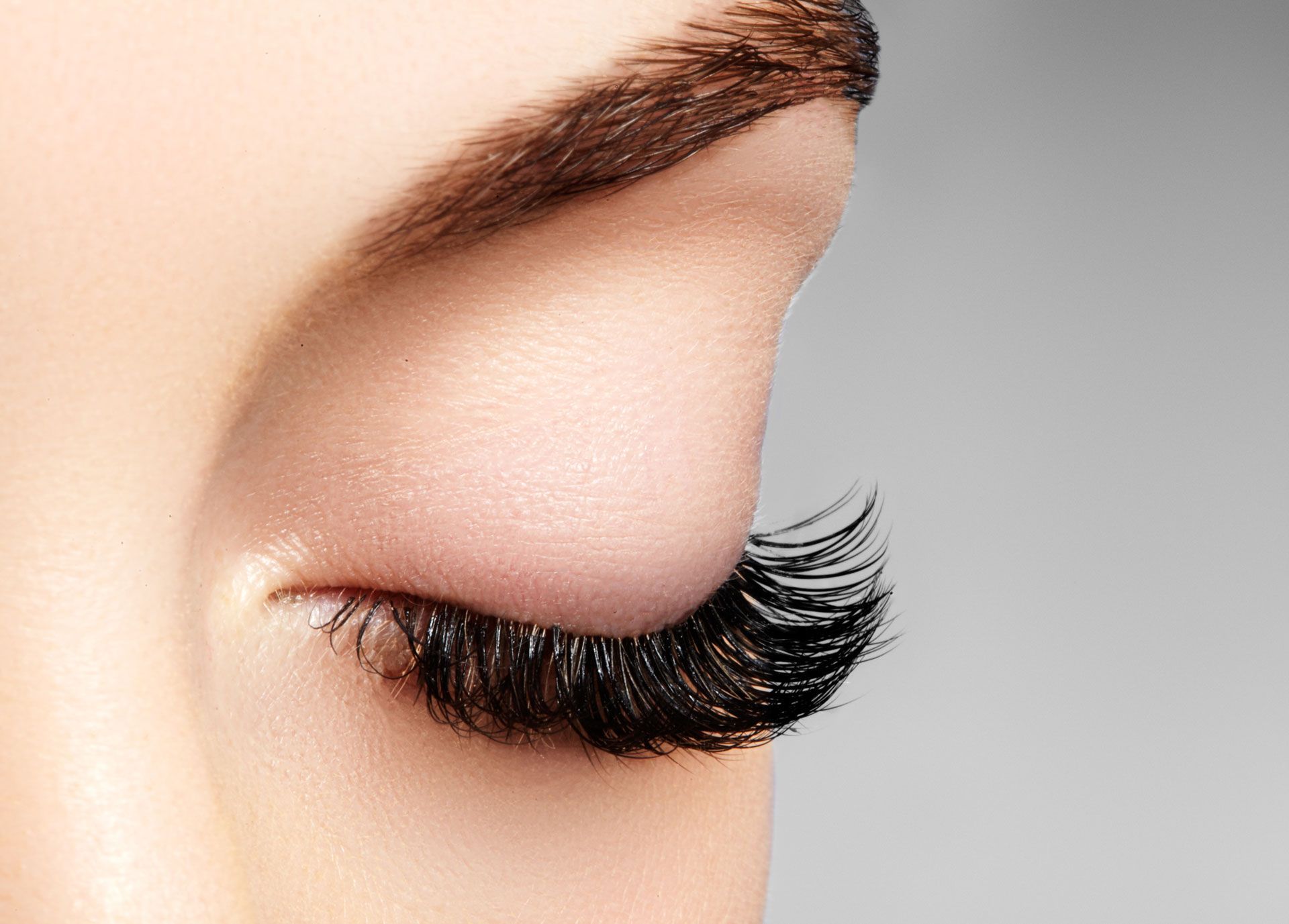 Closed eye with long, dark eyelashes and a groomed eyebrow.