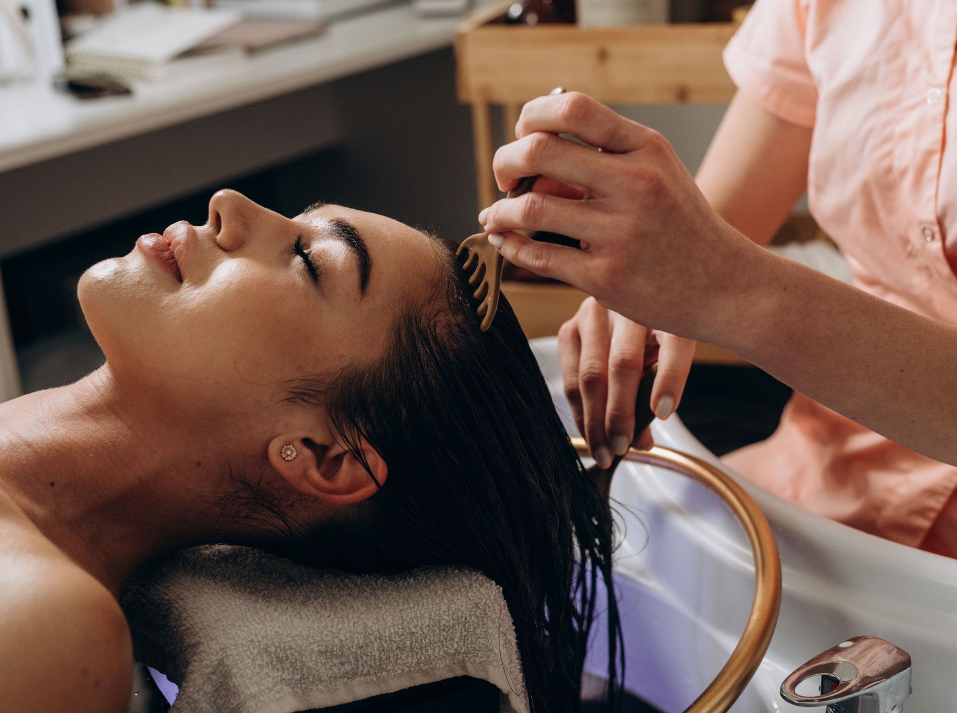 Woman having hair treated in salon; stylist applying product.