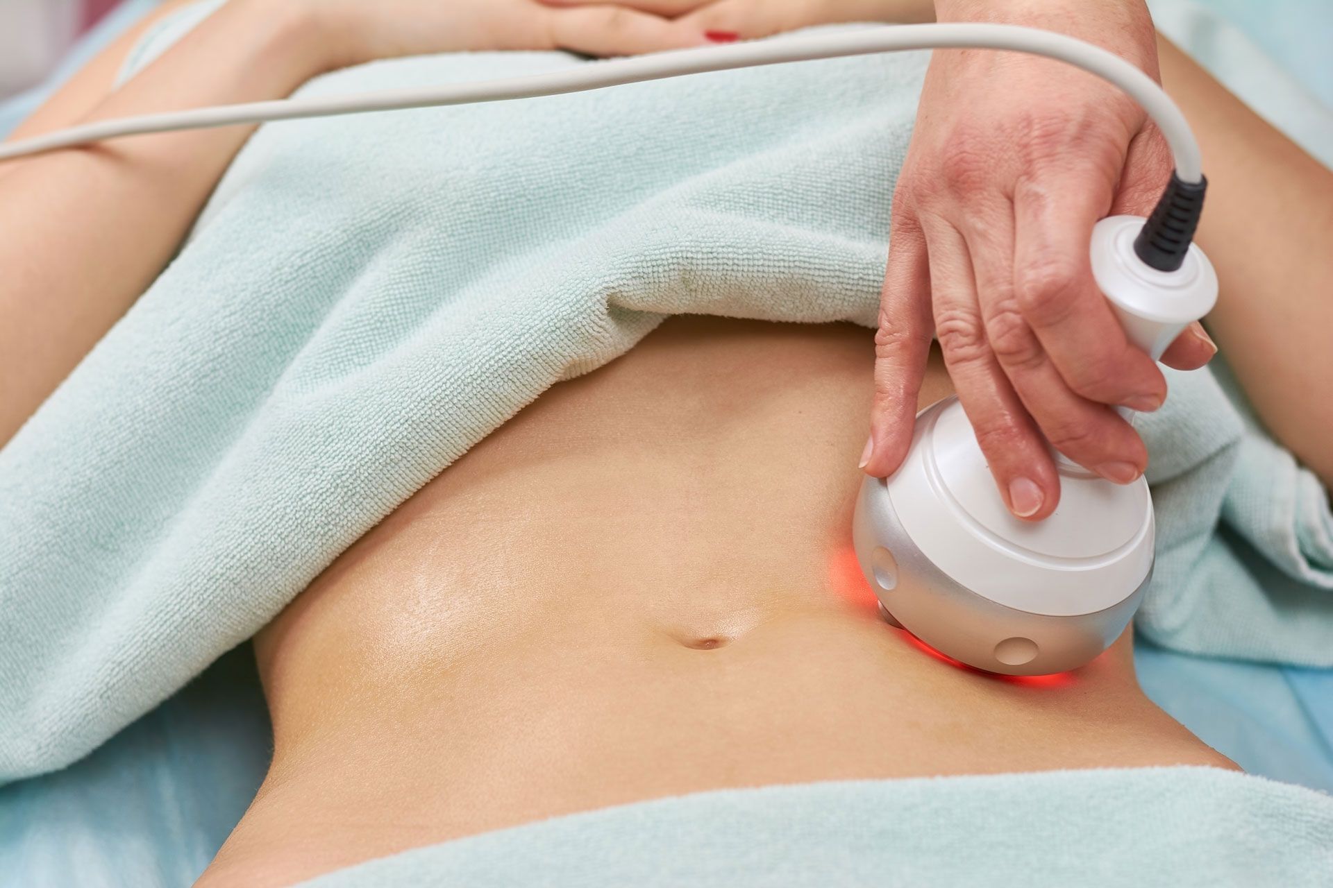 Person receiving a non-invasive body contouring treatment on their abdomen.