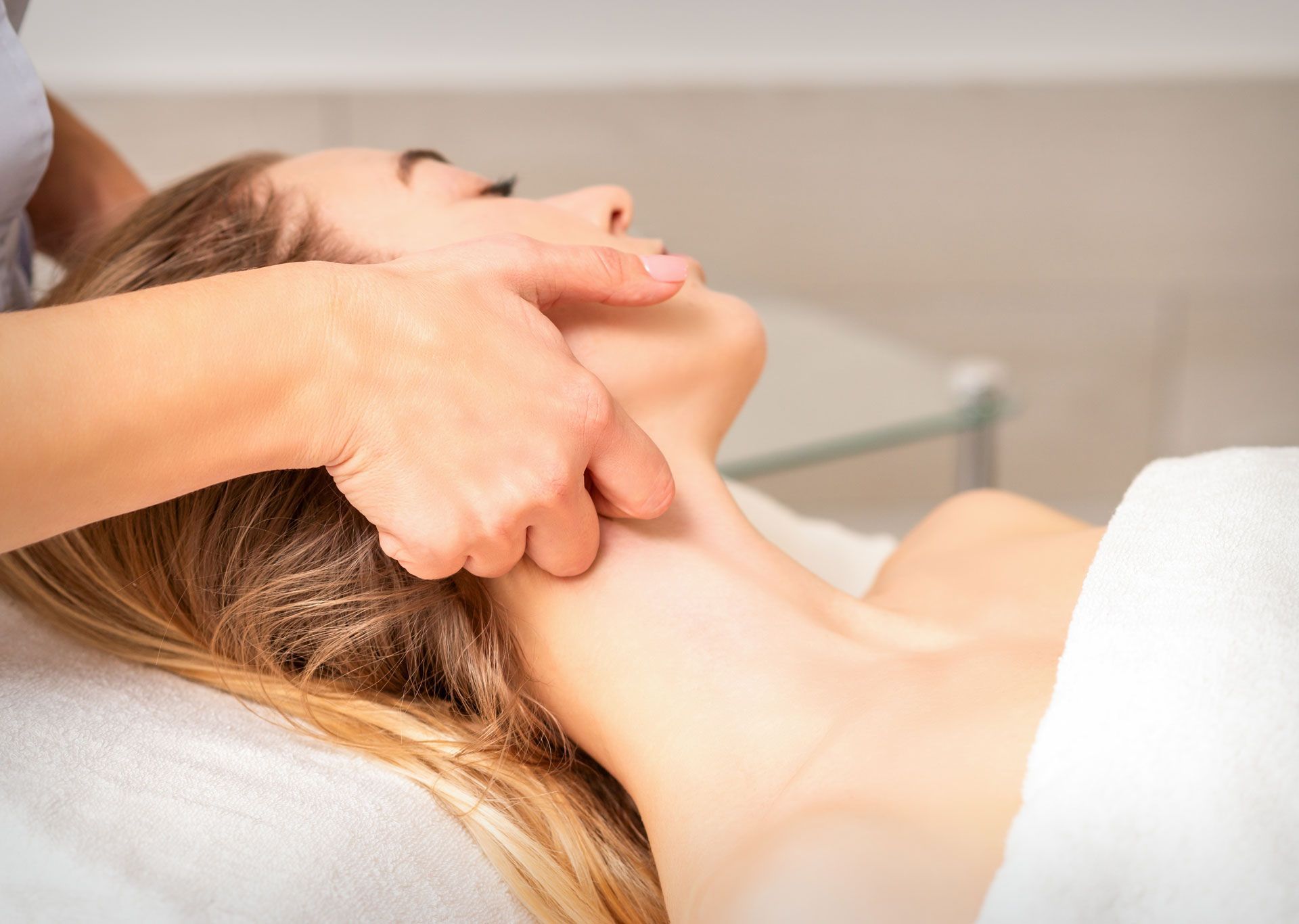 Woman receiving neck massage. Therapist's hand on her neck, indoors, close up.