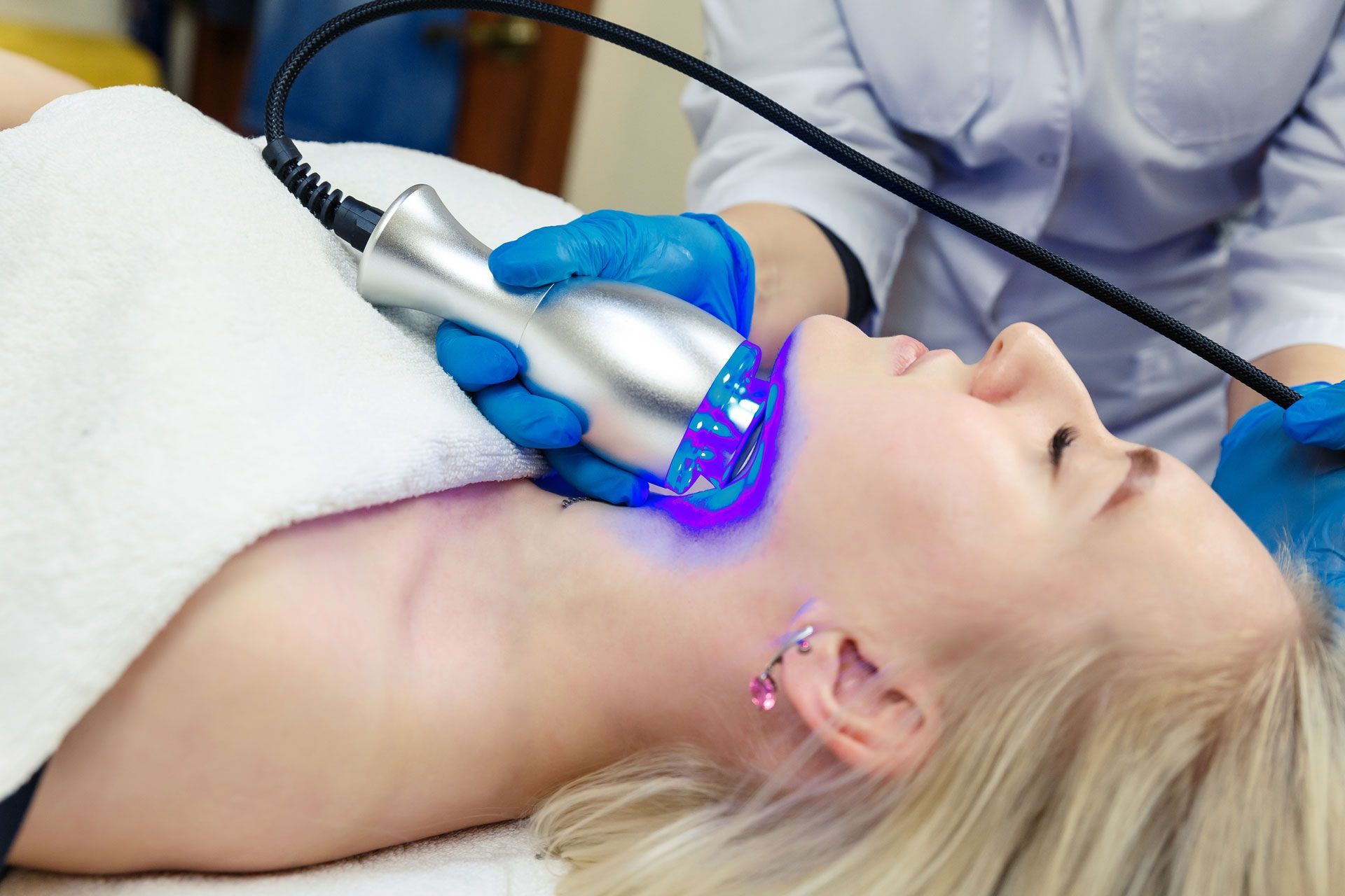 Person receiving facial treatment with a blue light device.