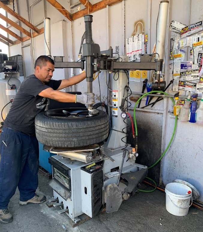 A technician uses a tire mounting machine to work on a car tire in a repair shop.