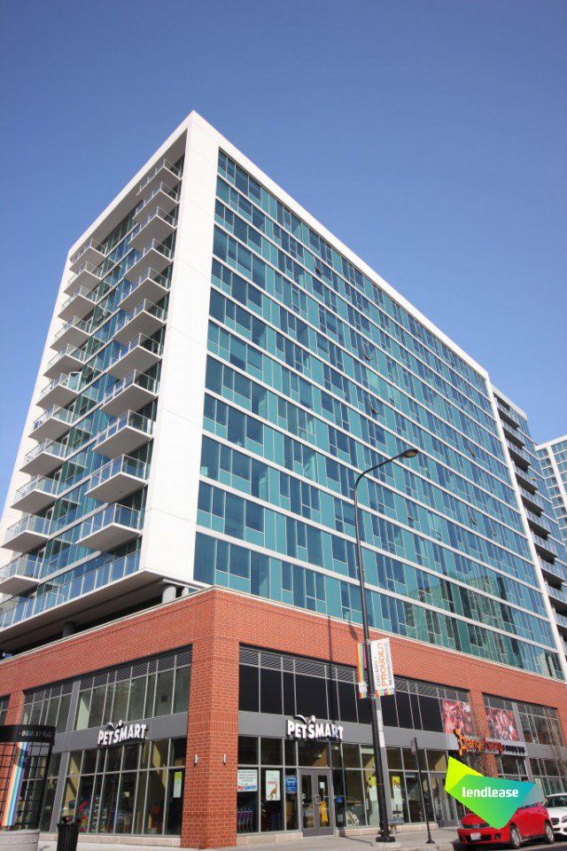 A tall building with a lot of windows and a red car parked in front of it.