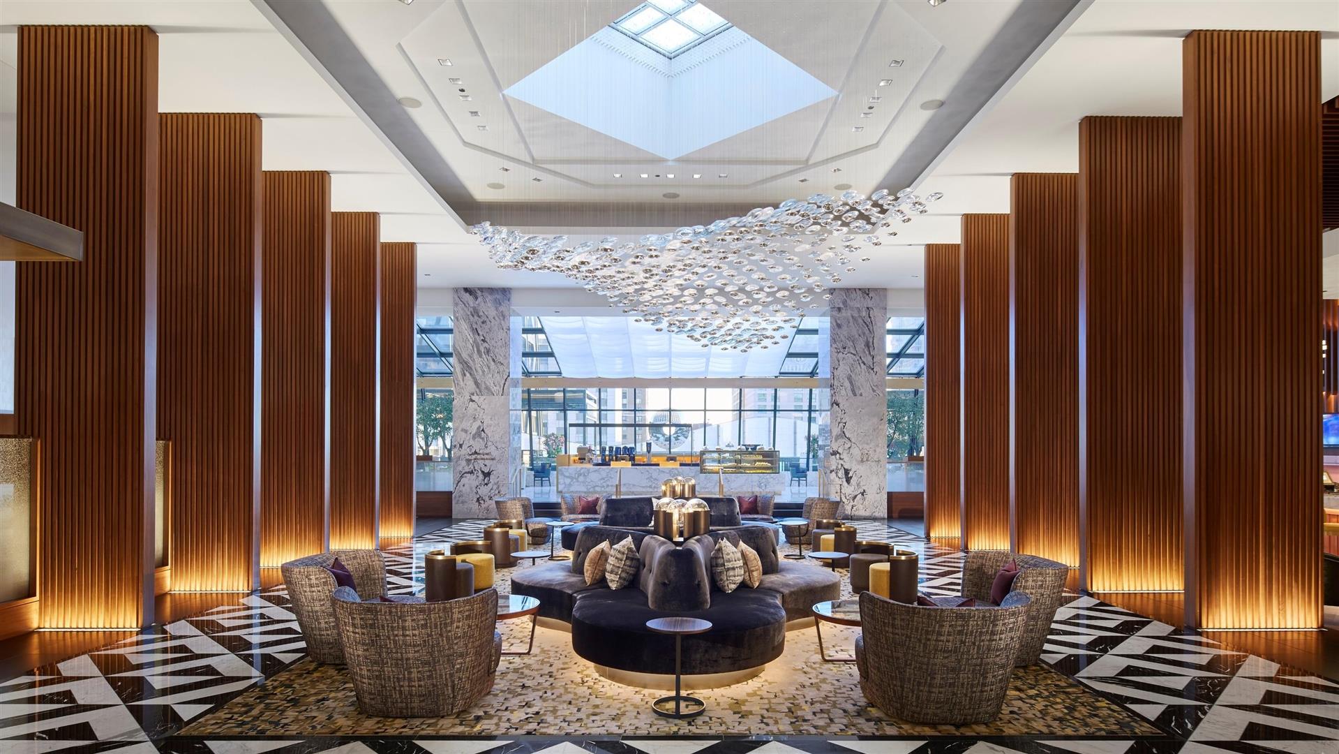 A large lobby with a lot of furniture and a chandelier hanging from the ceiling.