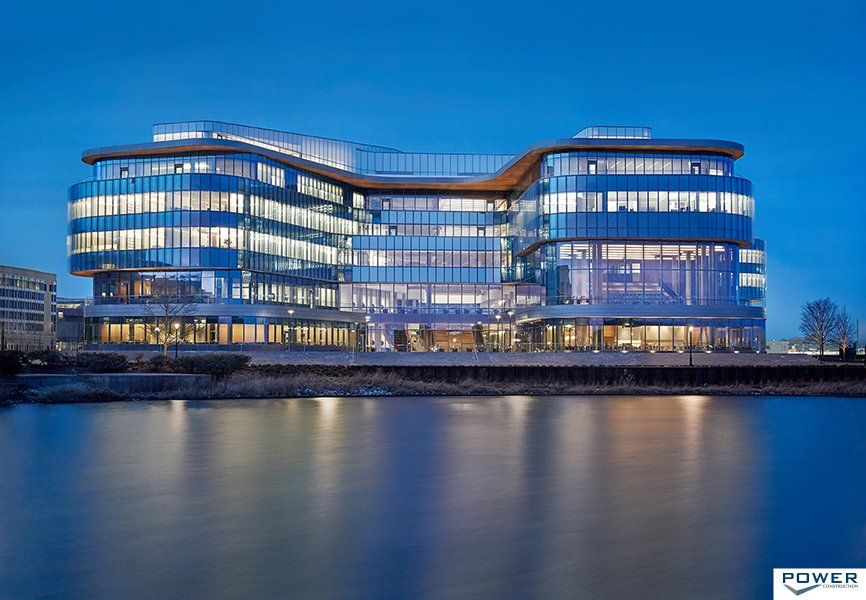 A large building is sitting next to a body of water at night.