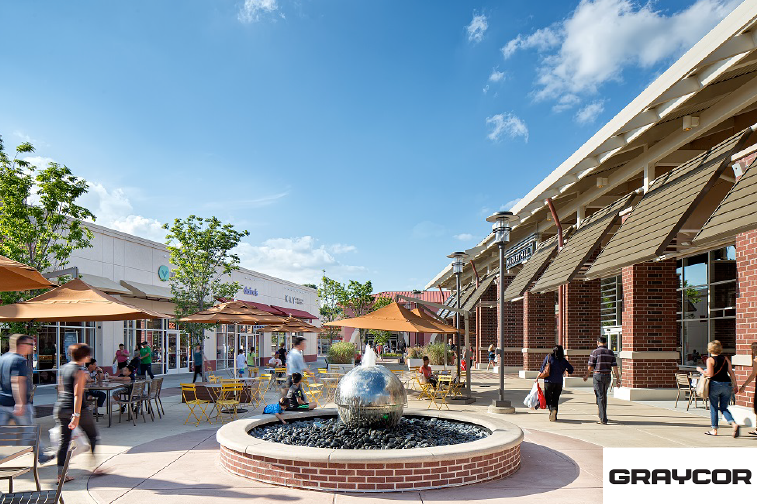 A group of people are walking around a fountain in a shopping mall.