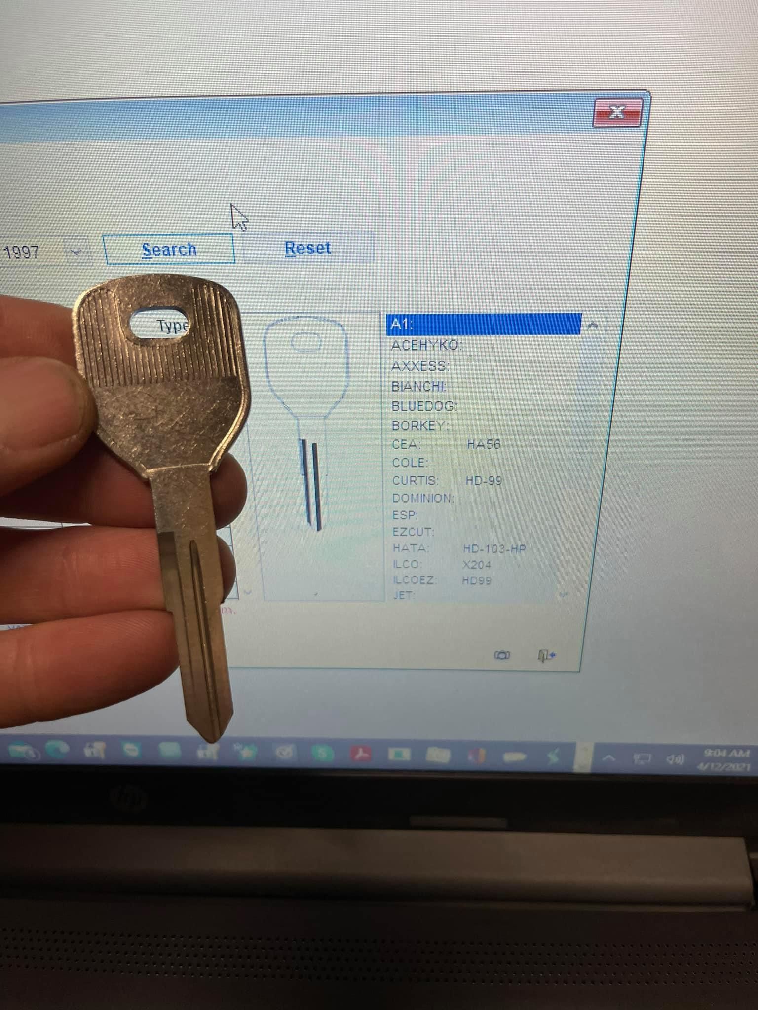 A person is holding a key in front of a computer screen.