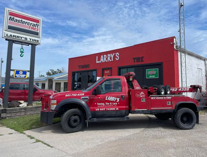 A red tow truck is parked in front of larry 's tire
