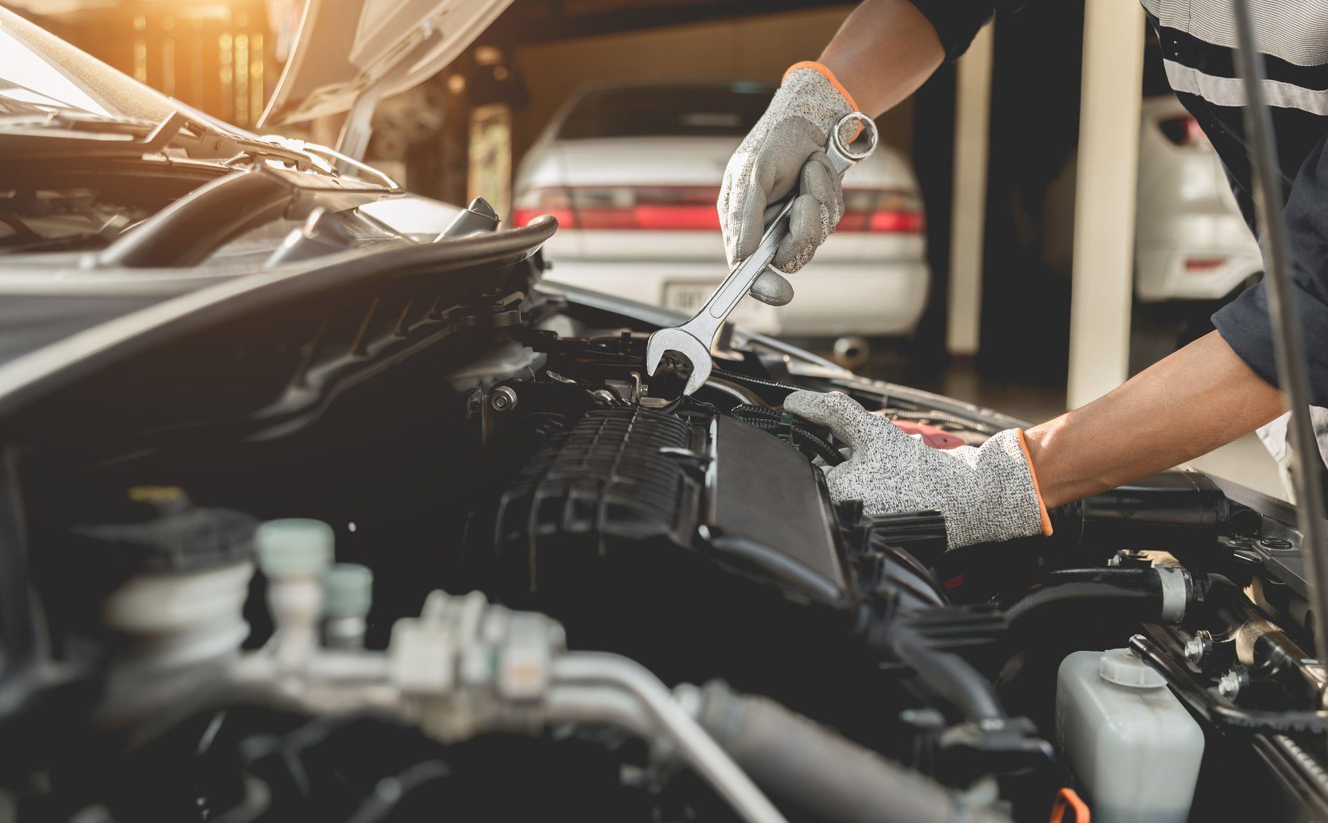 A man is working on the engine of a car with a wrench.