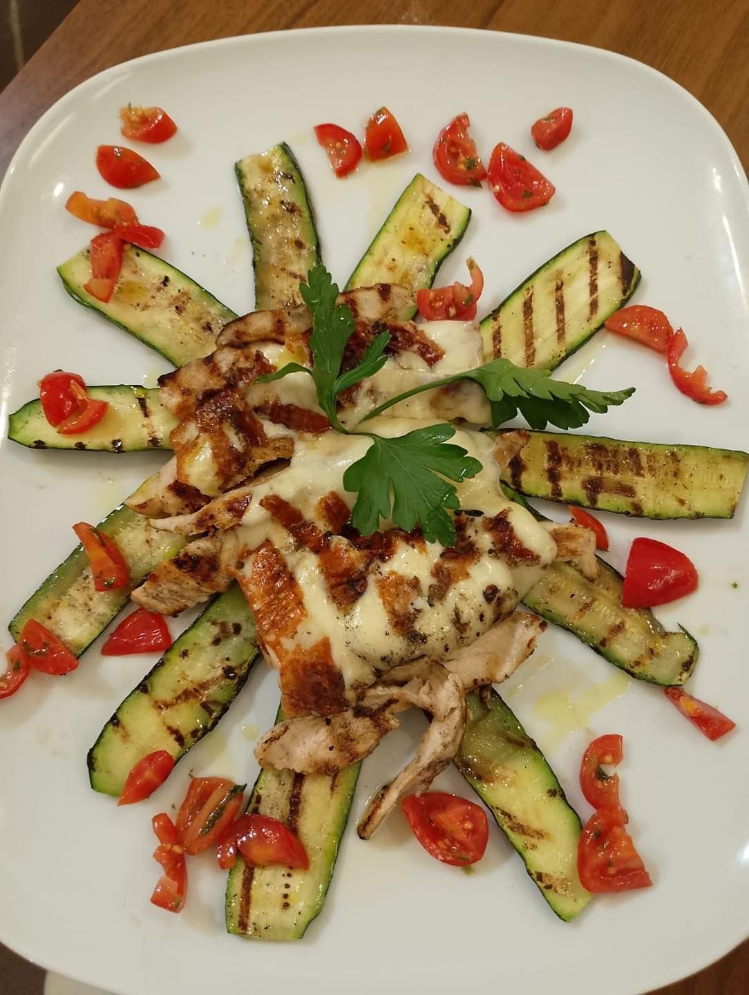 Un piatto bianco condito con zucchine grigliate e pomodori