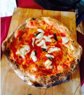 Una pizza con salsa di pomodoro e cipolle su un tagliere di legno