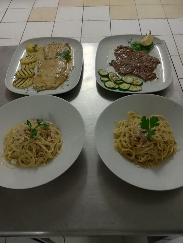 Due piatti di pasta e due piatti di carne sono su un tavolo.