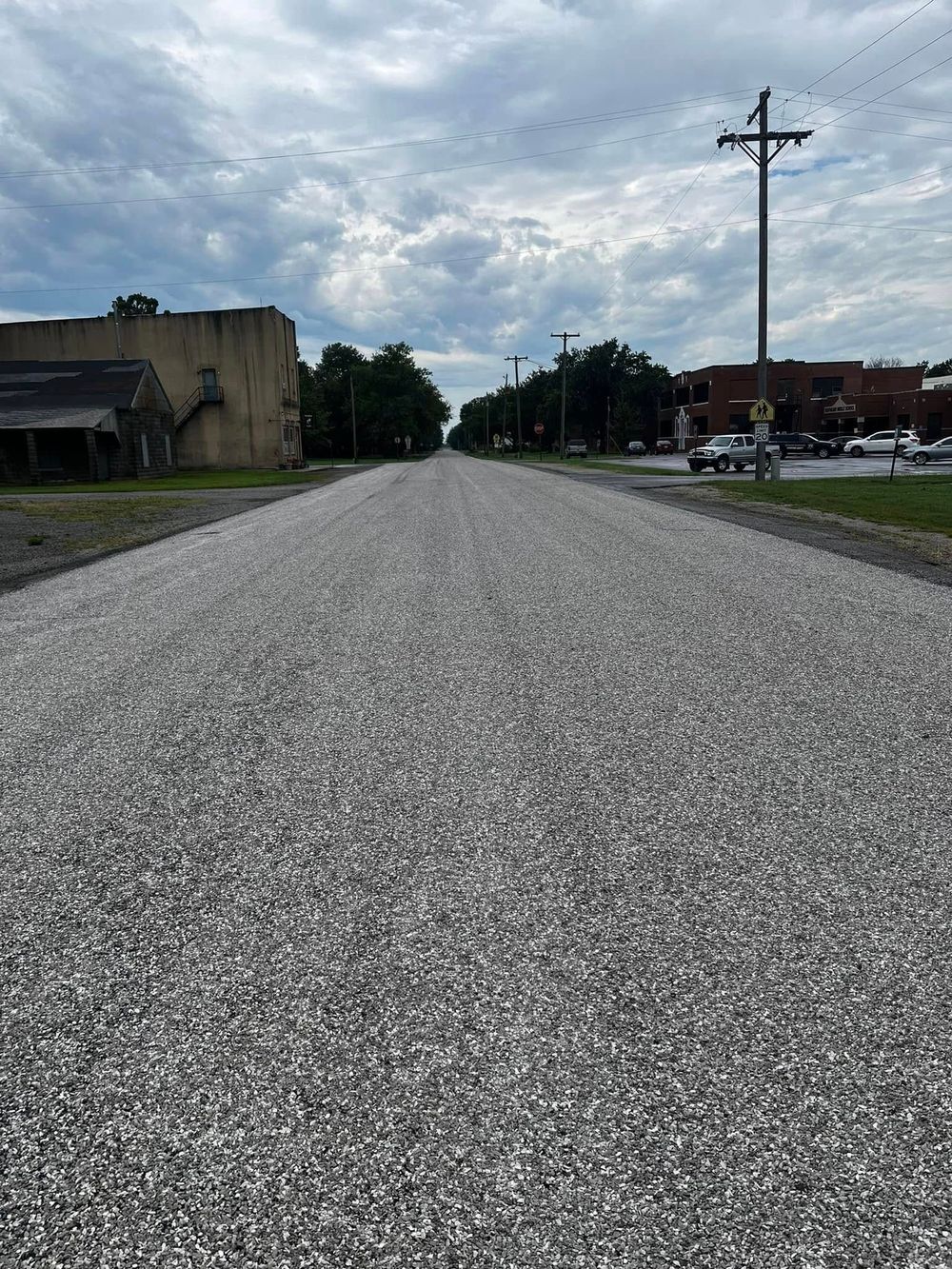 A road with a lot of gravel on it and a building in the background.