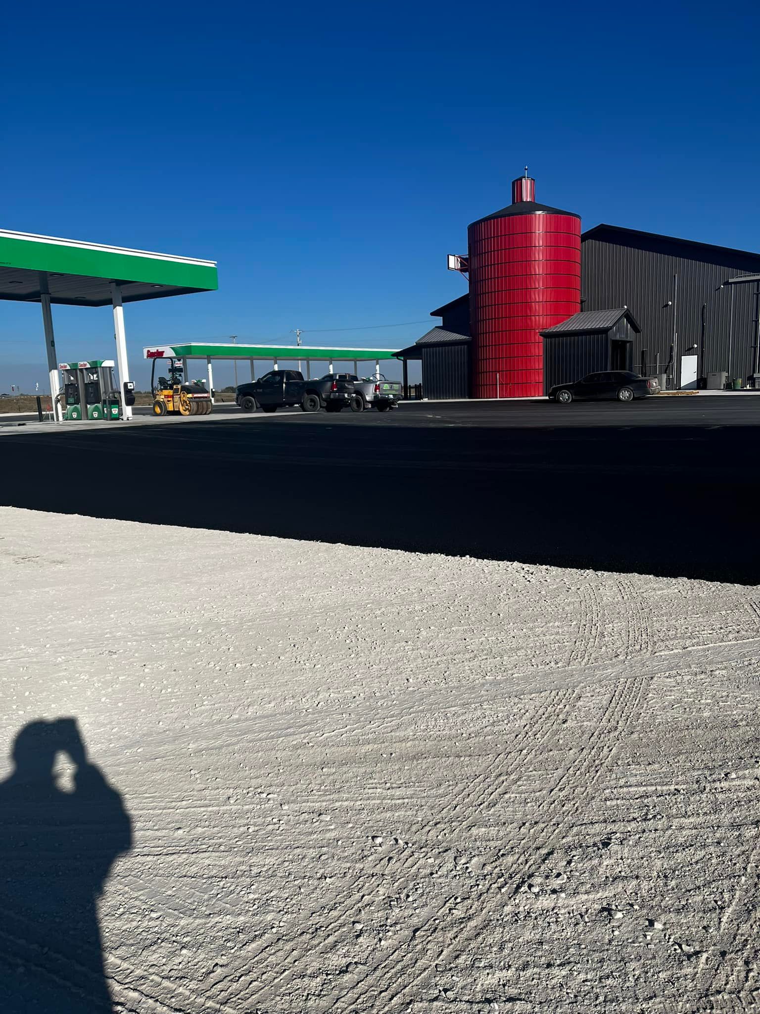 A shadow of a person taking a picture of a gas station