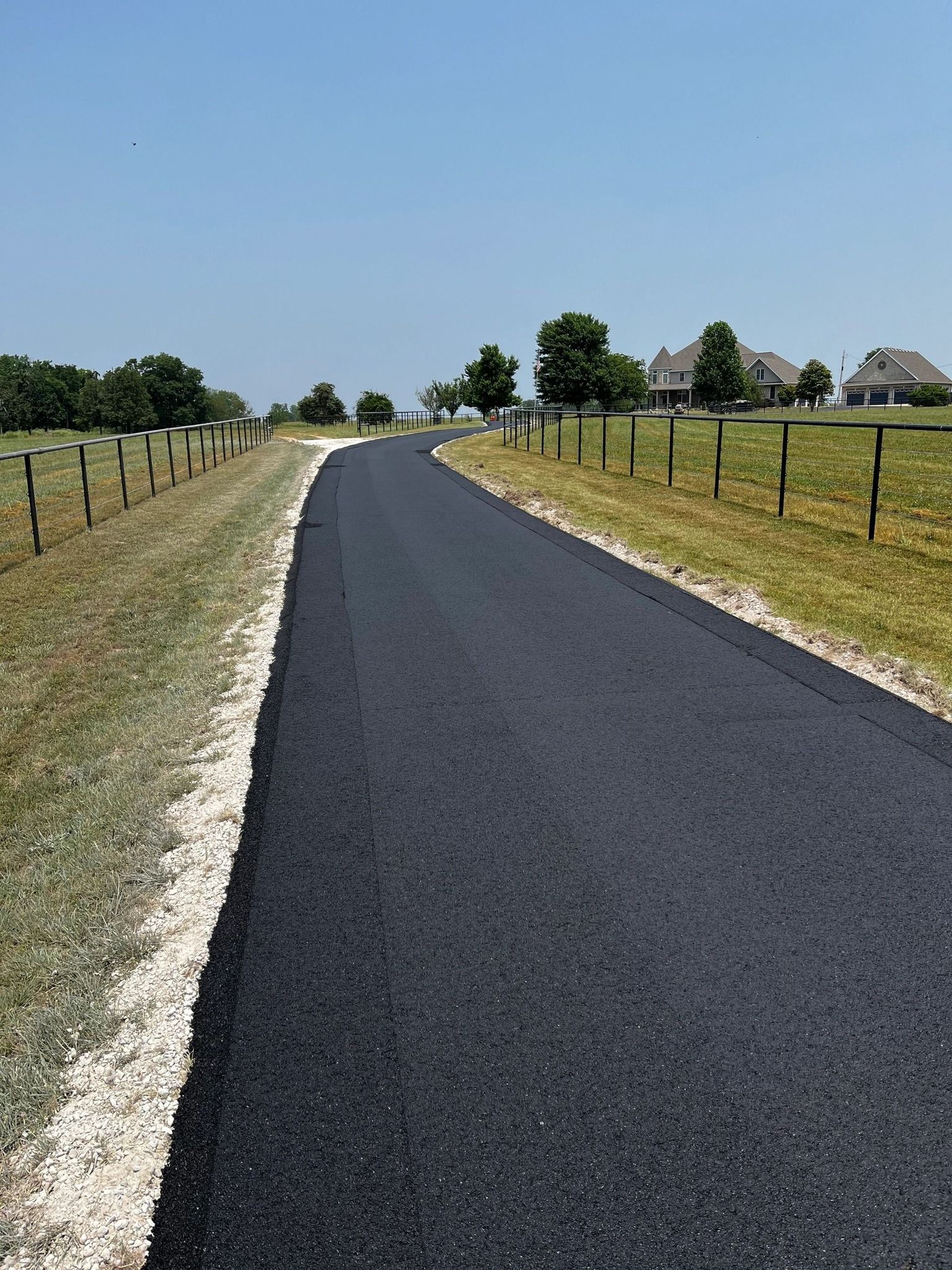 A road that is going through a grassy field