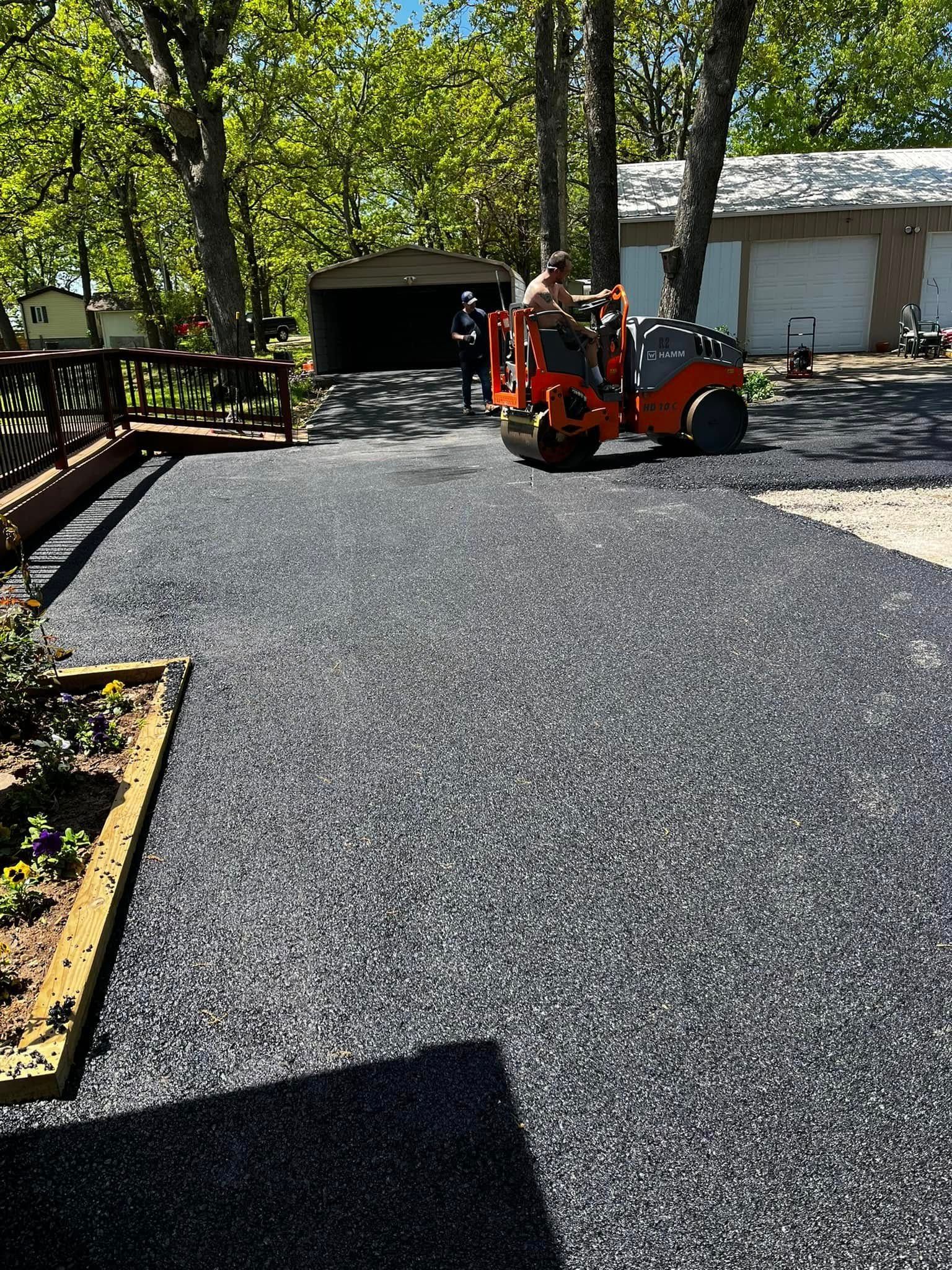 A man is driving a tractor down a driveway.