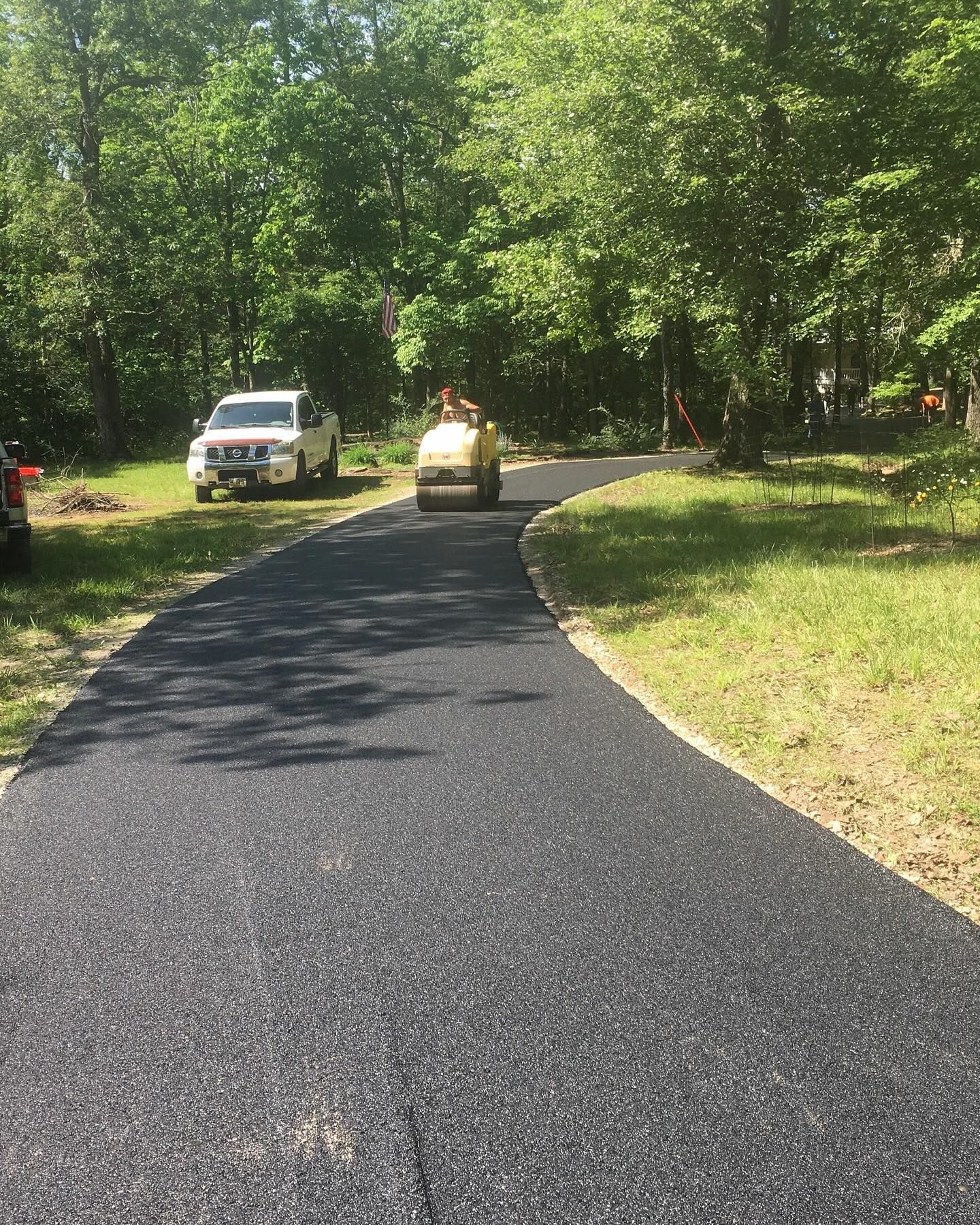 A car is driving down a road in the woods.