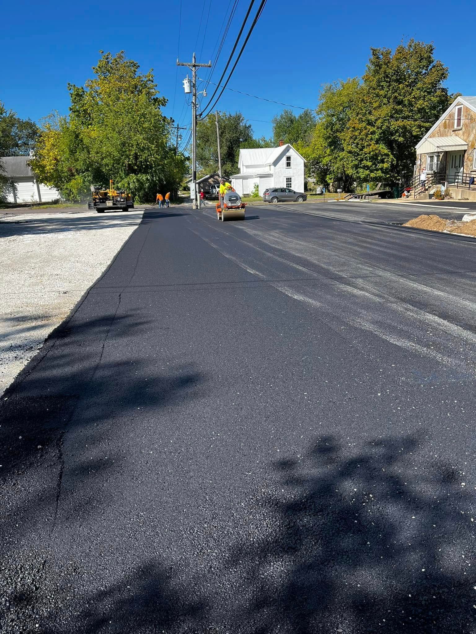A road is being paved in a small town on a sunny day.