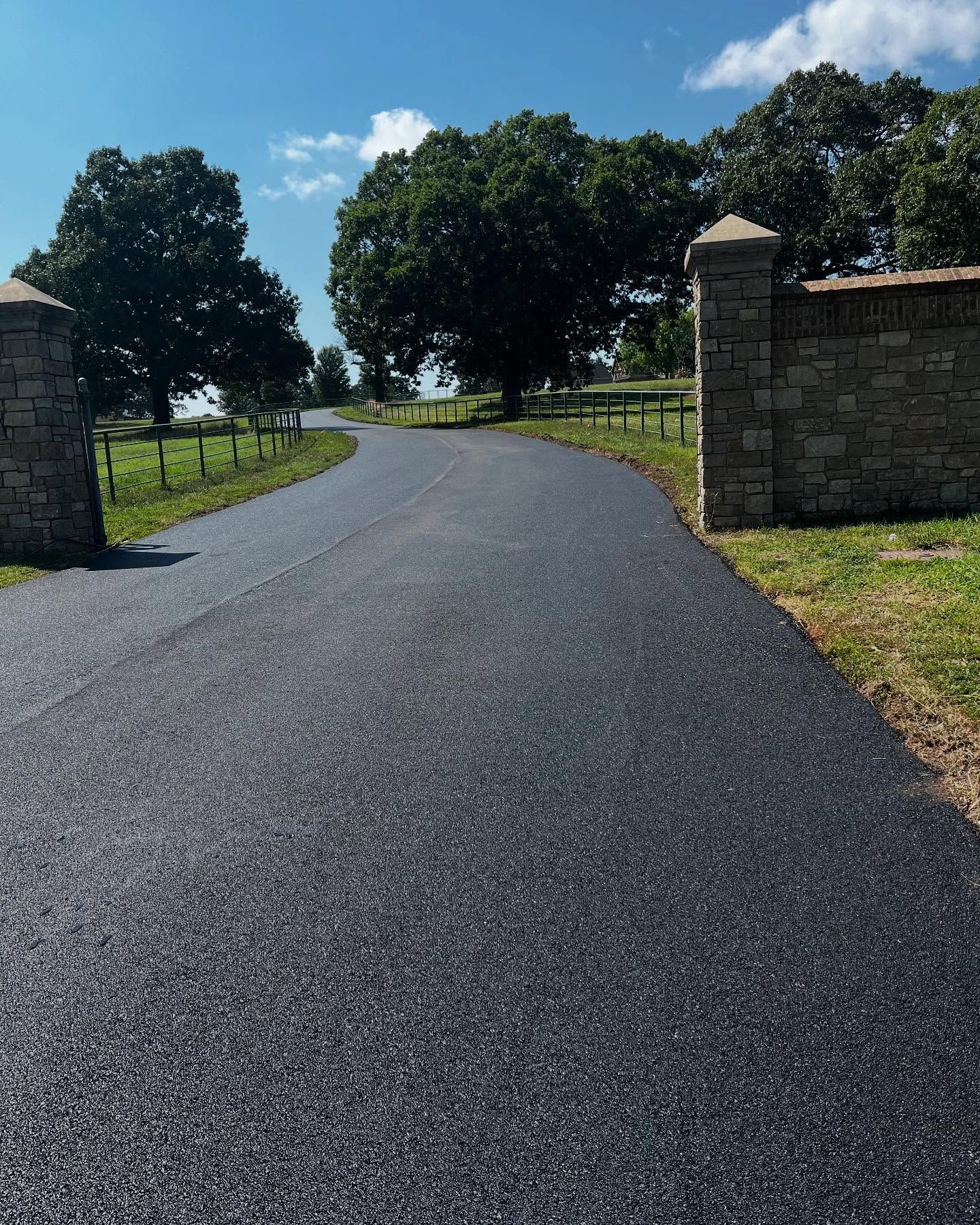A road with trees on both sides and a stone wall