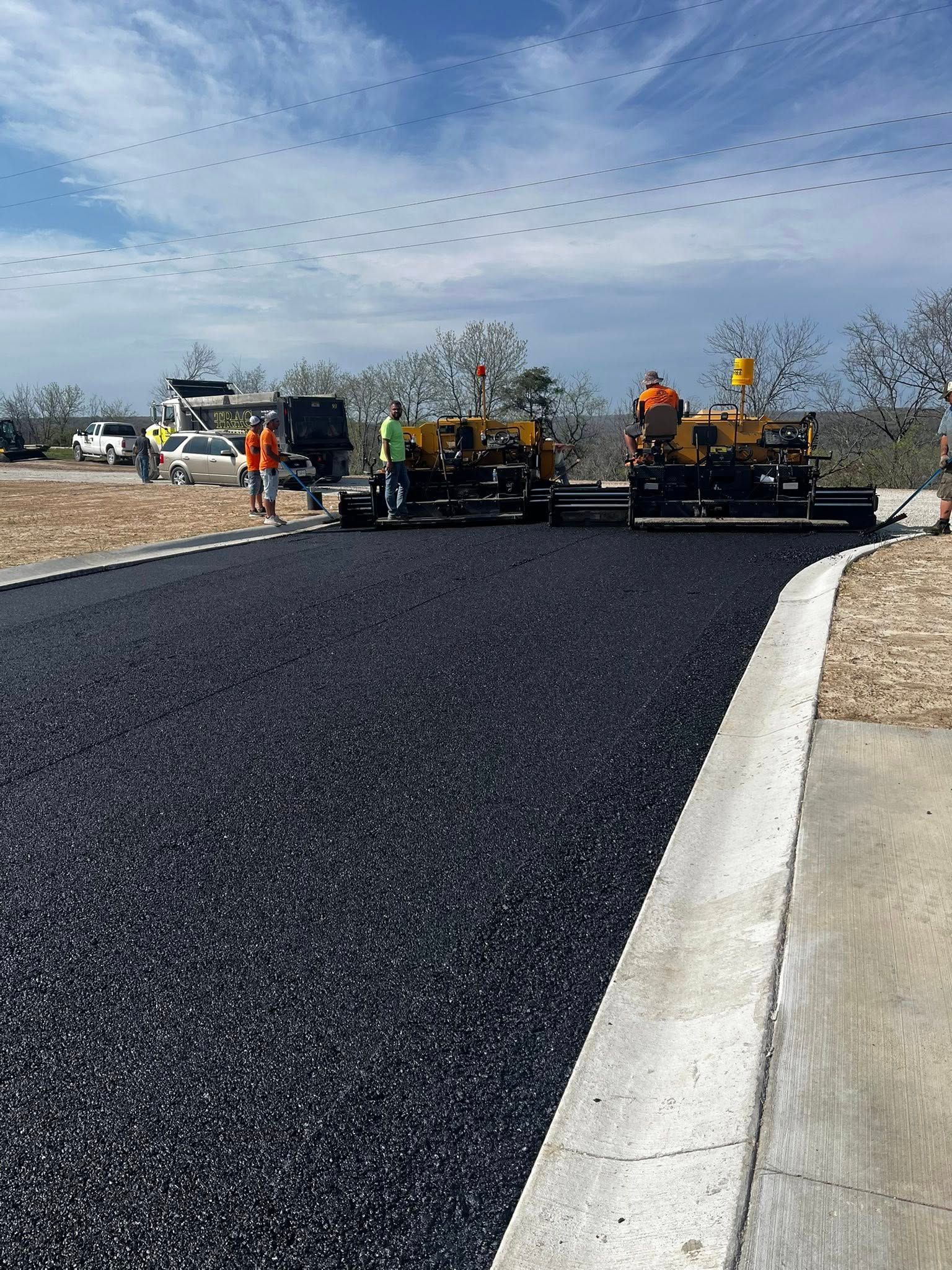 A group of construction workers are laying asphalt on a road.