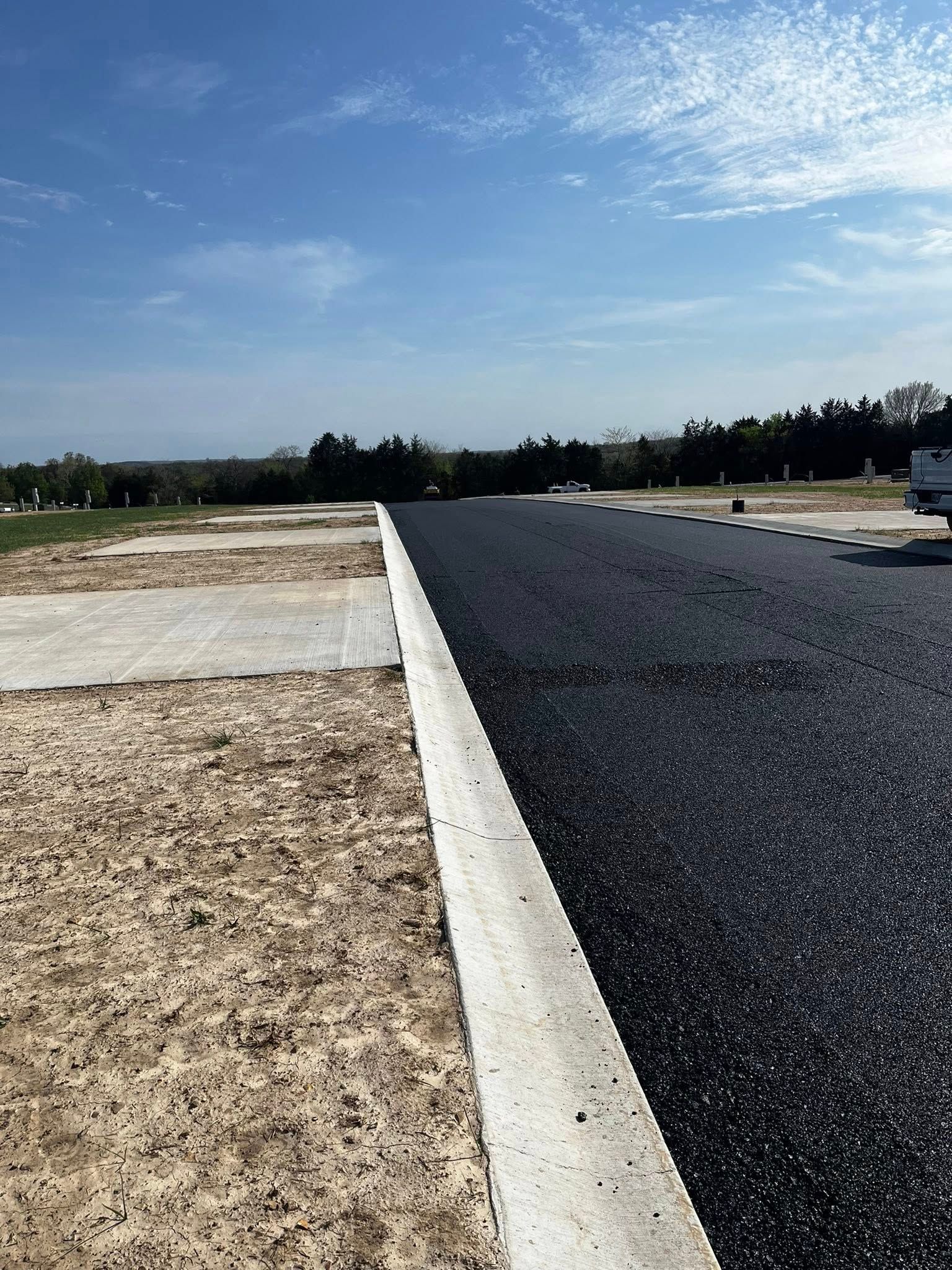 A car is parked on the side of a road next to a dirt field.