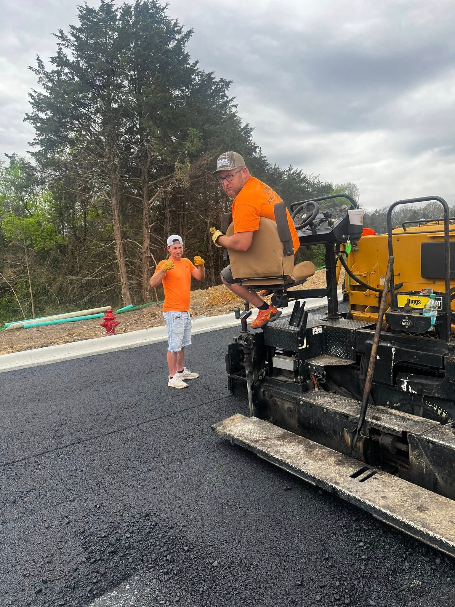 A man is sitting on a machine while another man stands next to him.