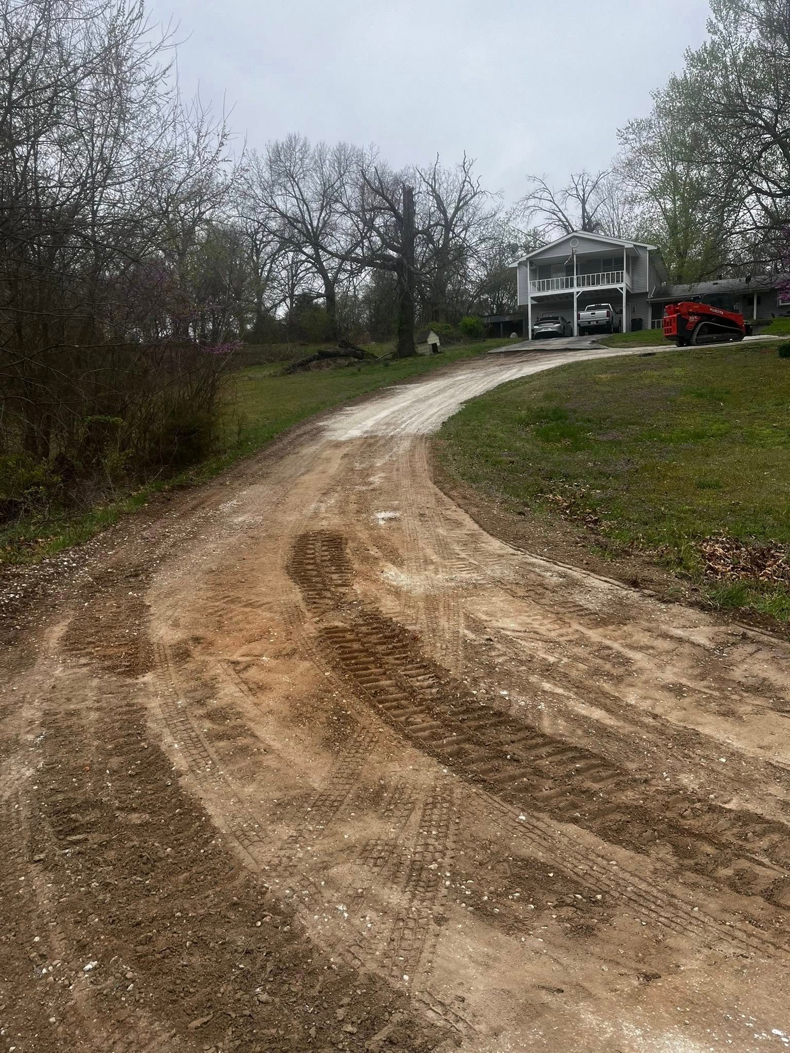 A dirt road leading to a house on a hill.