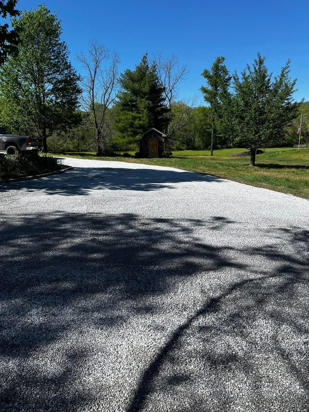 A gravel driveway with a car parked in the middle of it.