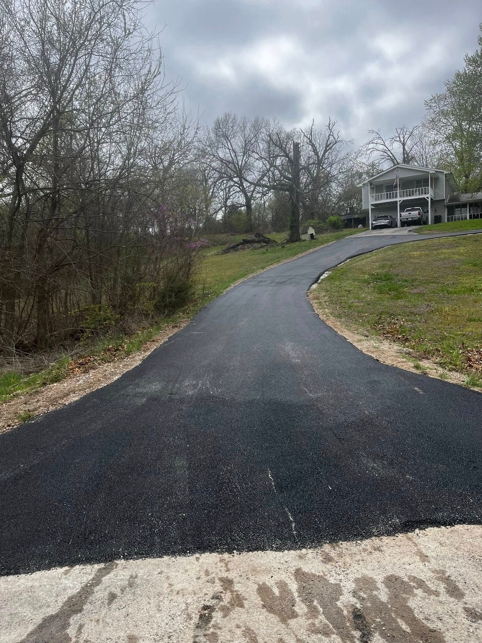 A newly paved driveway leading to a house on a hill.