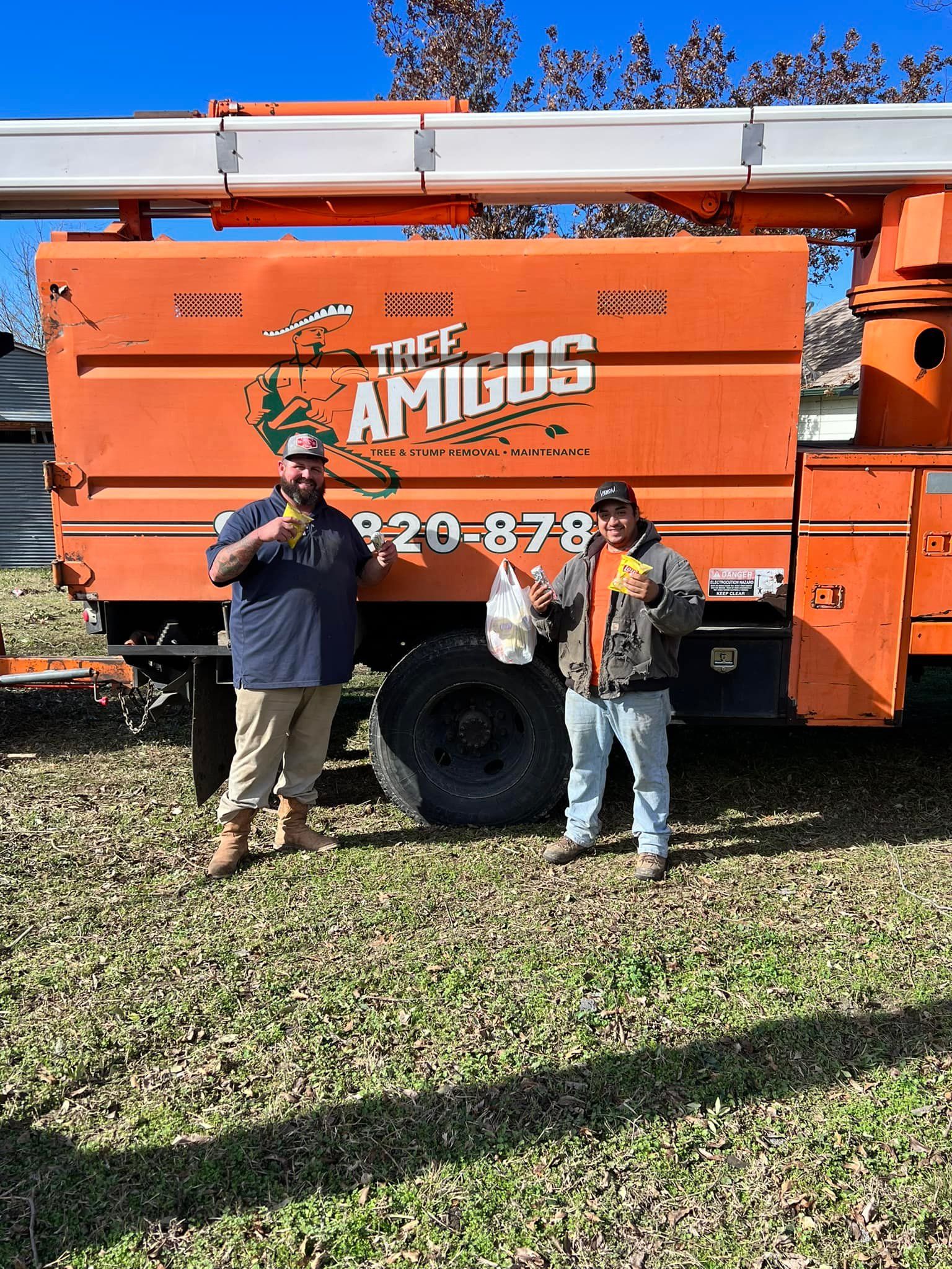 Two people stand in front of an orange truck with 