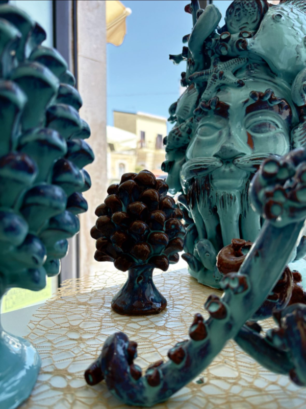 Sculture in ceramica blu e marrone esposte in una vetrina, tra cui un volto e forme simili ad alberi.