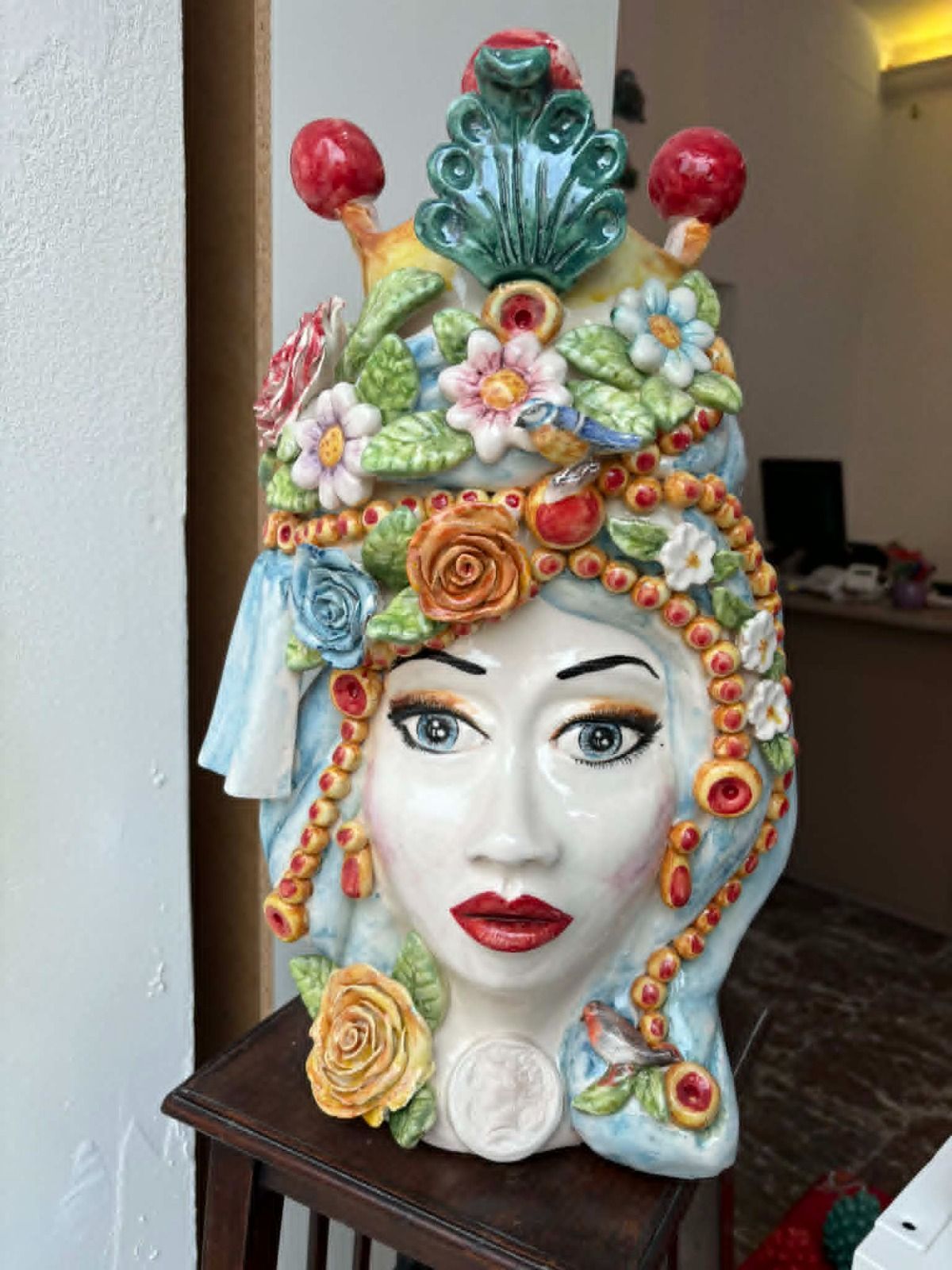 Sculture in ceramica raffiguranti teste di re e di regina con una pigna in ceramica verde tra di esse.
