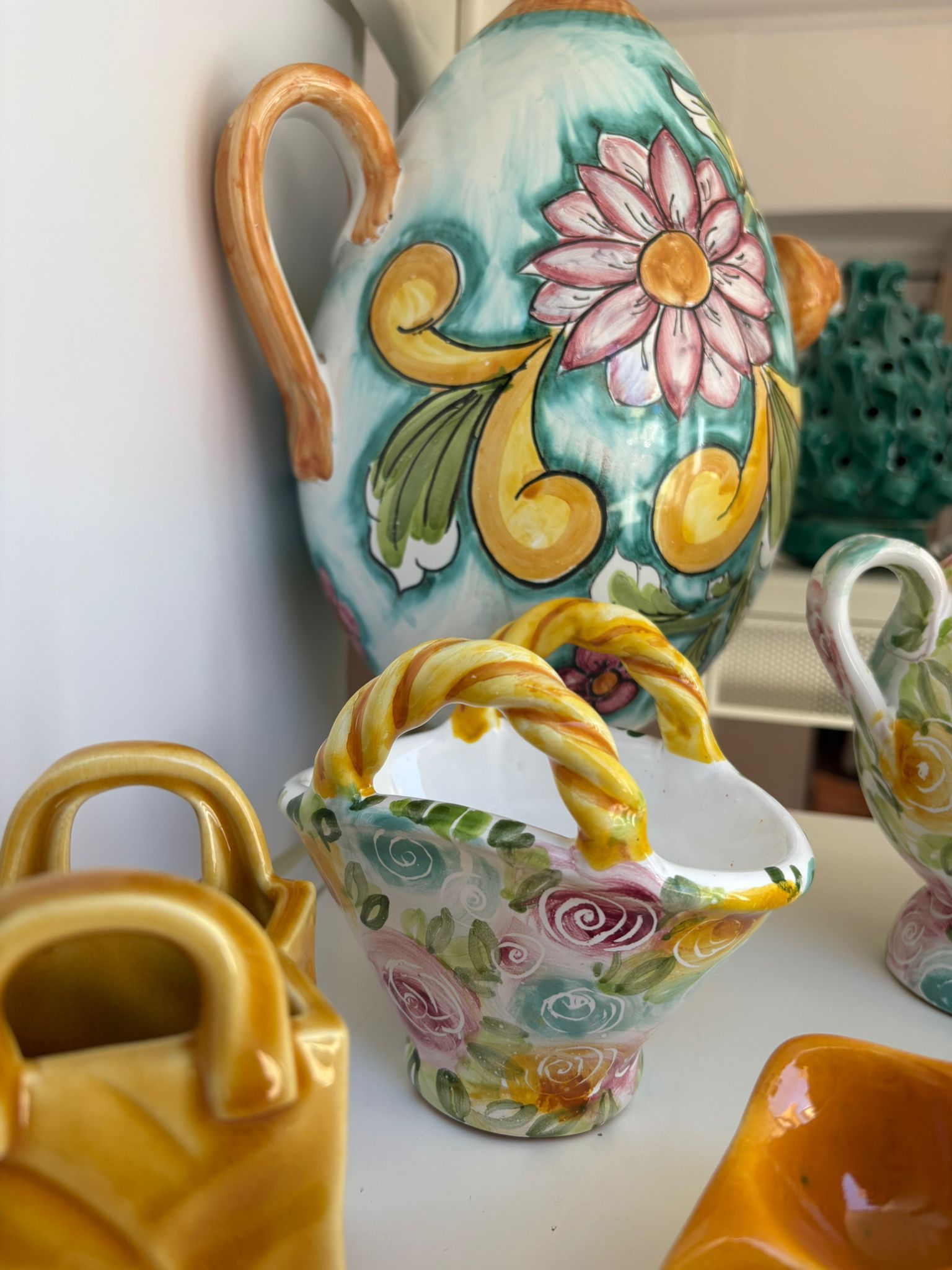 Presepi in ceramica con figure dipinte, in vari colori, esposte su una superficie bianca.