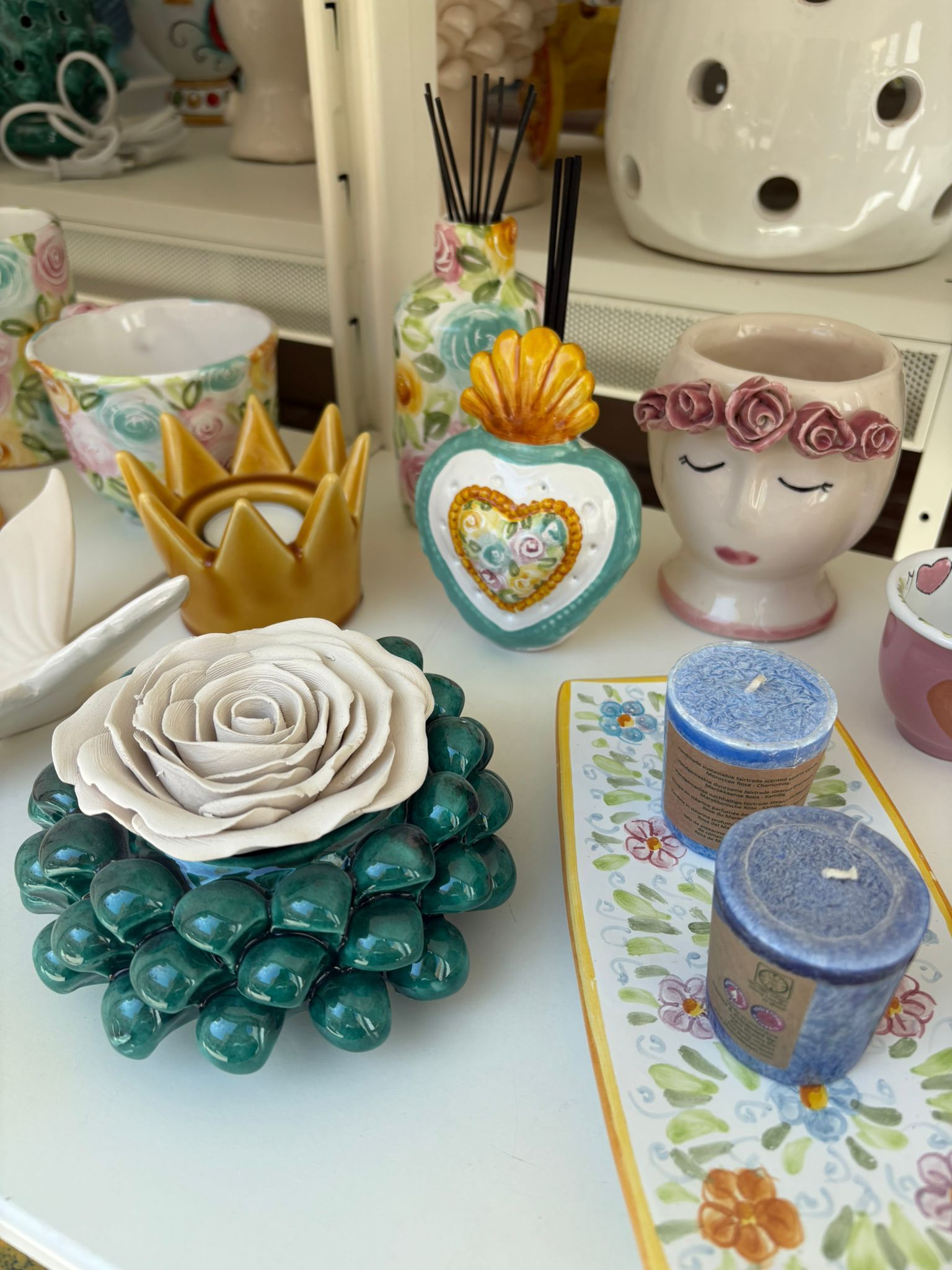 Tre uova di Pasqua in ceramica raffiguranti coniglietti con facce dipinte e motivi floreali su una lastra di legno.