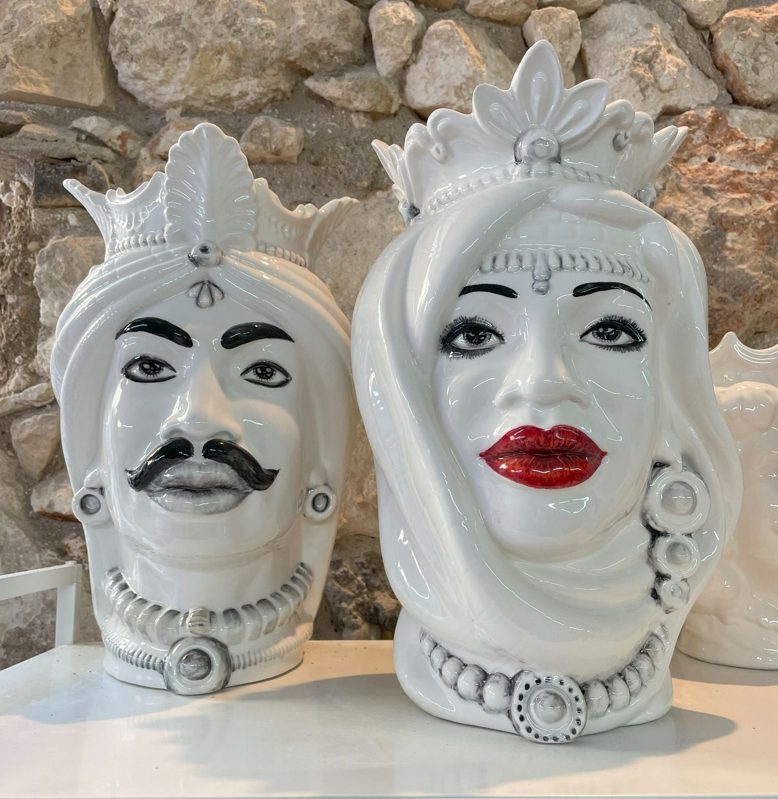 Due vasi in ceramica raffiguranti una testa di uomo e una di donna, di colore bianco, con tratti del viso dettagliati e corone.