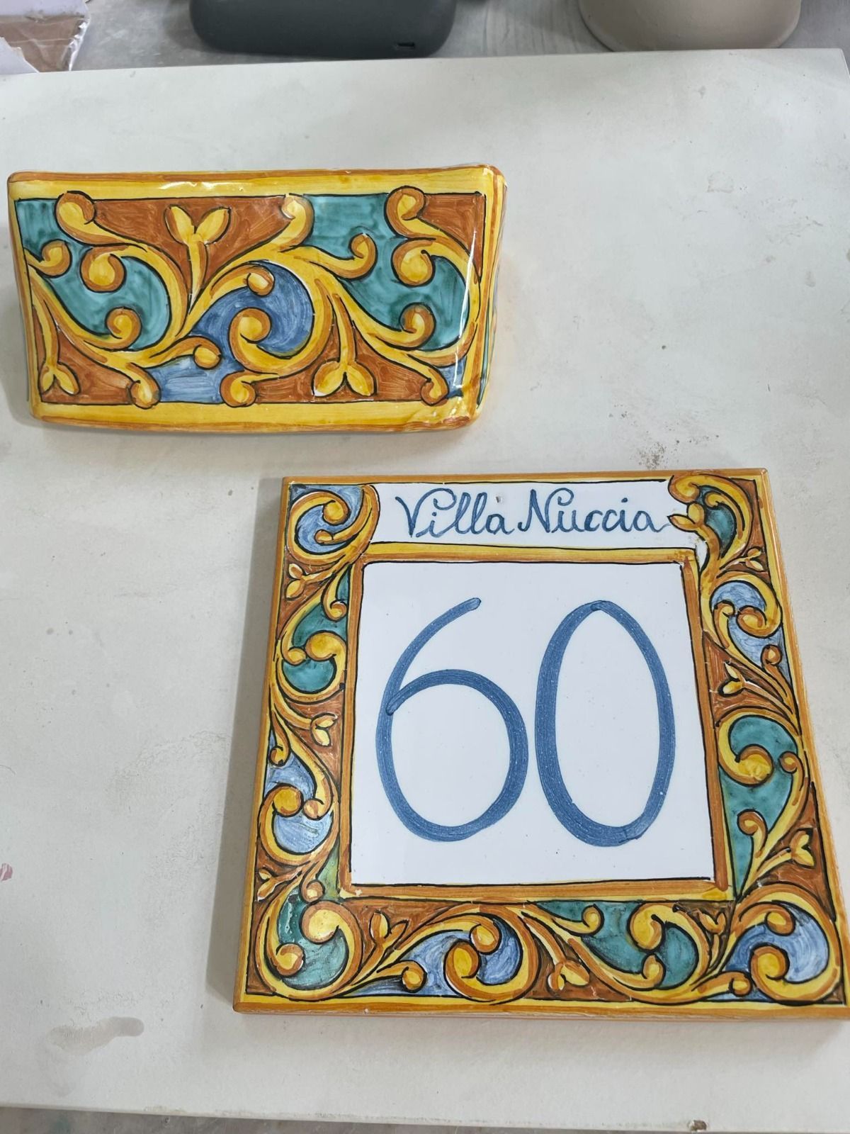 Targa in ceramica con numero civico e bordo decorato, raffigurante