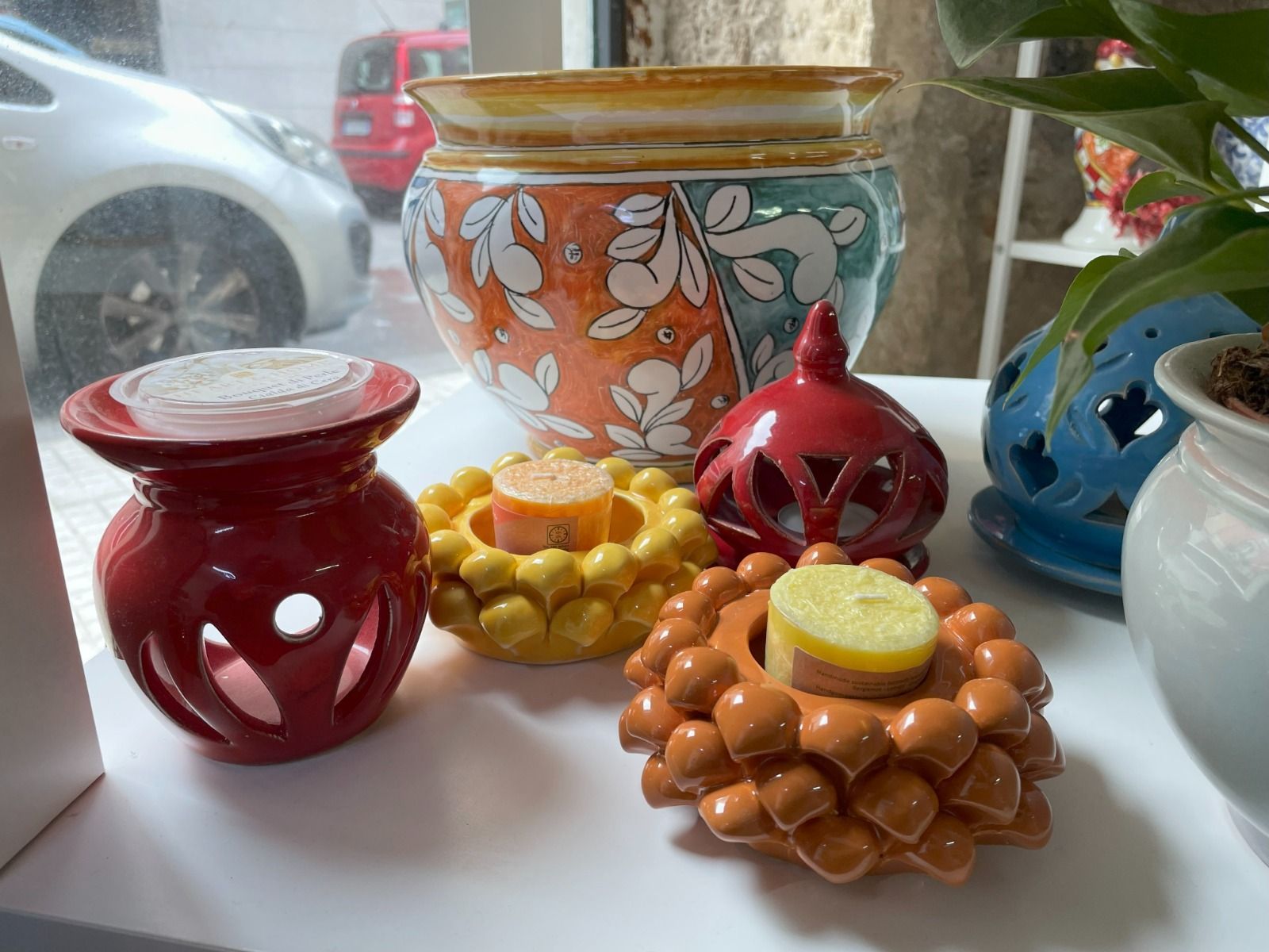 Collezione di coloratissimi oggetti in ceramica esposti su un tavolo di legno. Include piccole scatole, animali, cuori e posacenere.