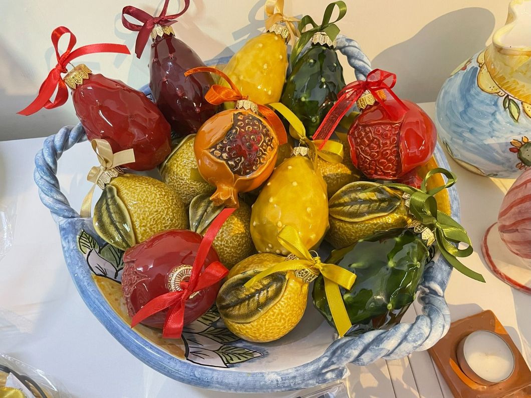 Un cesto traboccante di decorazioni natalizie colorate a forma di frutta.