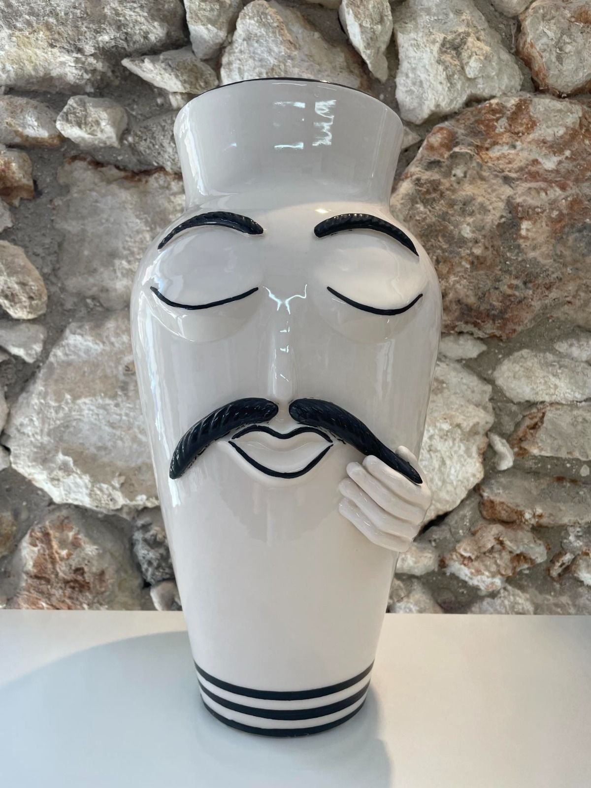 Uova di Pasqua in ceramica bianca, dipinte a mano con motivi floreali e di uccelli, su una mensola bianca.