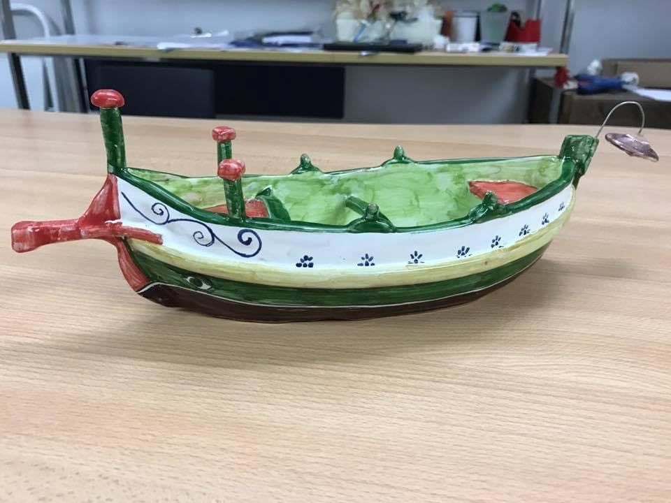 Decorazioni pasquali in ceramica: coniglietti, campanelli, uova e cactus su una mensola bianca, tutti dipinti a mano.