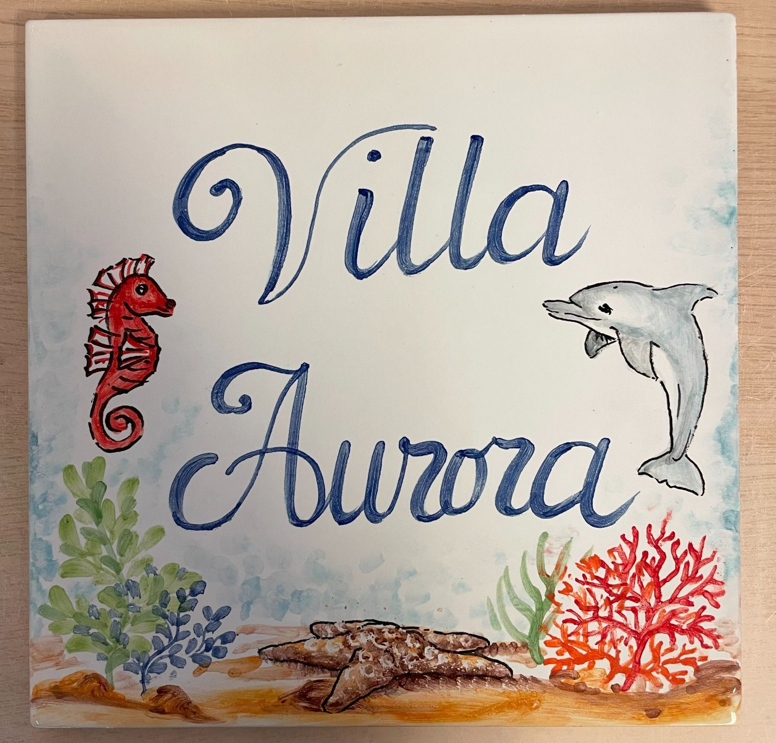 Numero civico uno in ceramica con limoni e foglie, dipinti in giallo, verde e bianco.