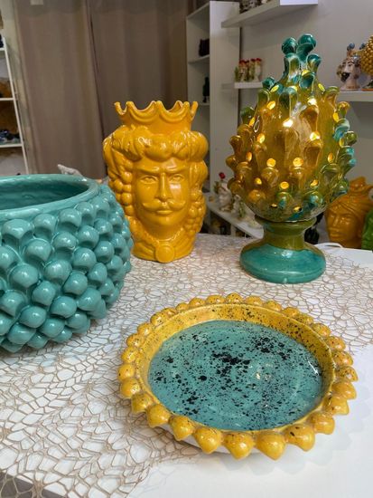 Cinque vasi decorativi in ​​ceramica con testa a forma di occhi chiusi e motivi floreali o vegetali sulla parte superiore.