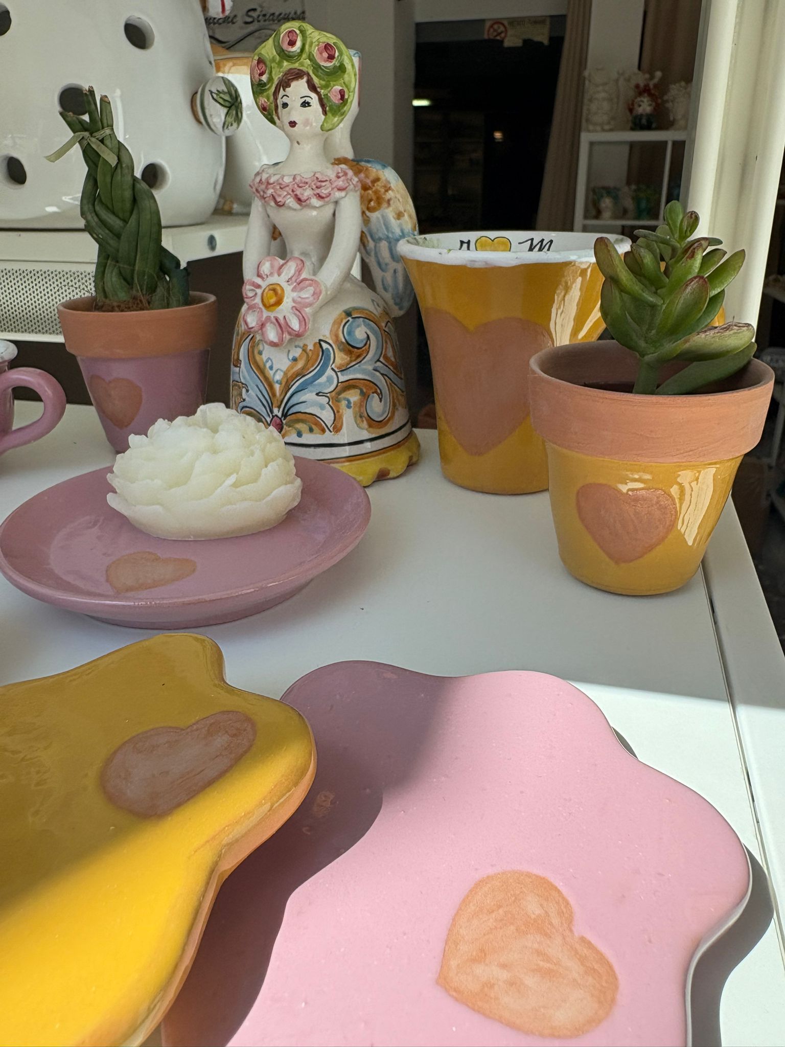 Presepi in ceramica con figure dipinte, in vari colori, esposte su una superficie bianca.