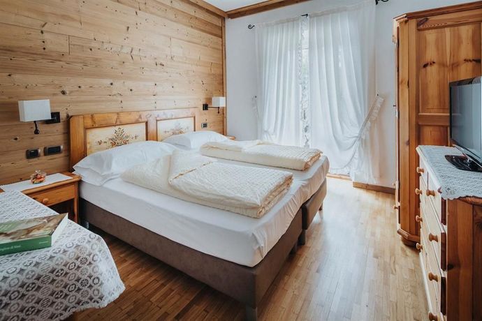 A hotel room with two beds , a dresser and a television.