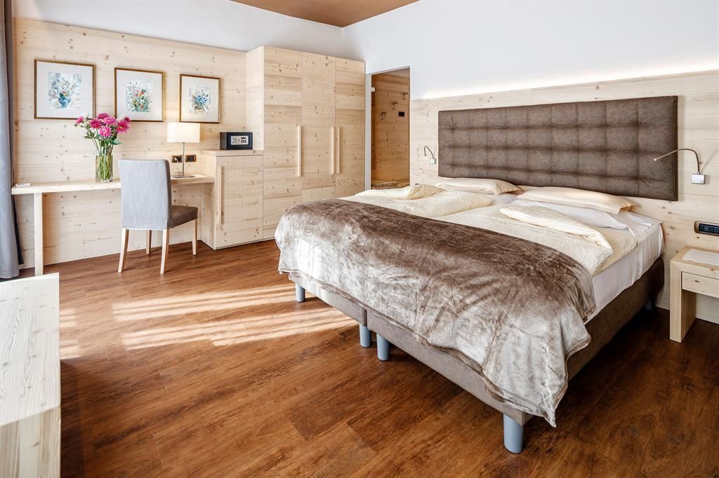 Una camera d'albergo con un letto grande, una scrivania e una sedia.